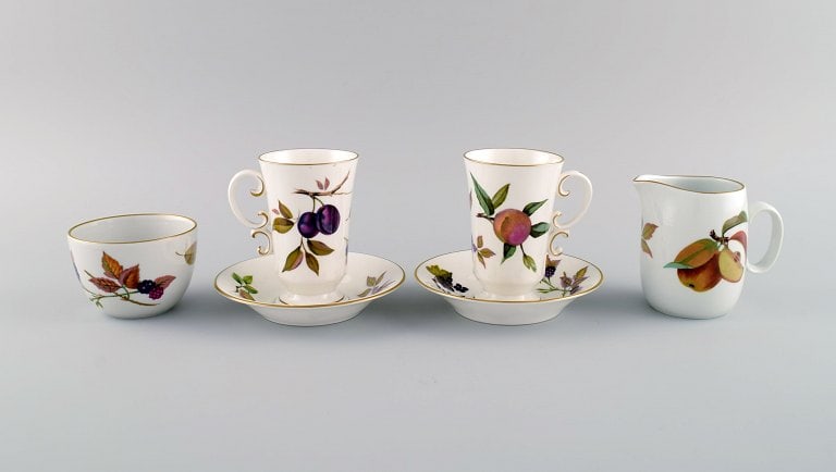 Royal Worcester, England. Two Evesham coffee cups with saucers, sugar bowl and cream jug in: Title: Royal Worcester, England. Two Evesham coffee cups with saucers, sugar bowl and cream jug in porcelain decorated with fruits and gold rim. 1980s. Description: Royal Worcester, England. Two Evesh