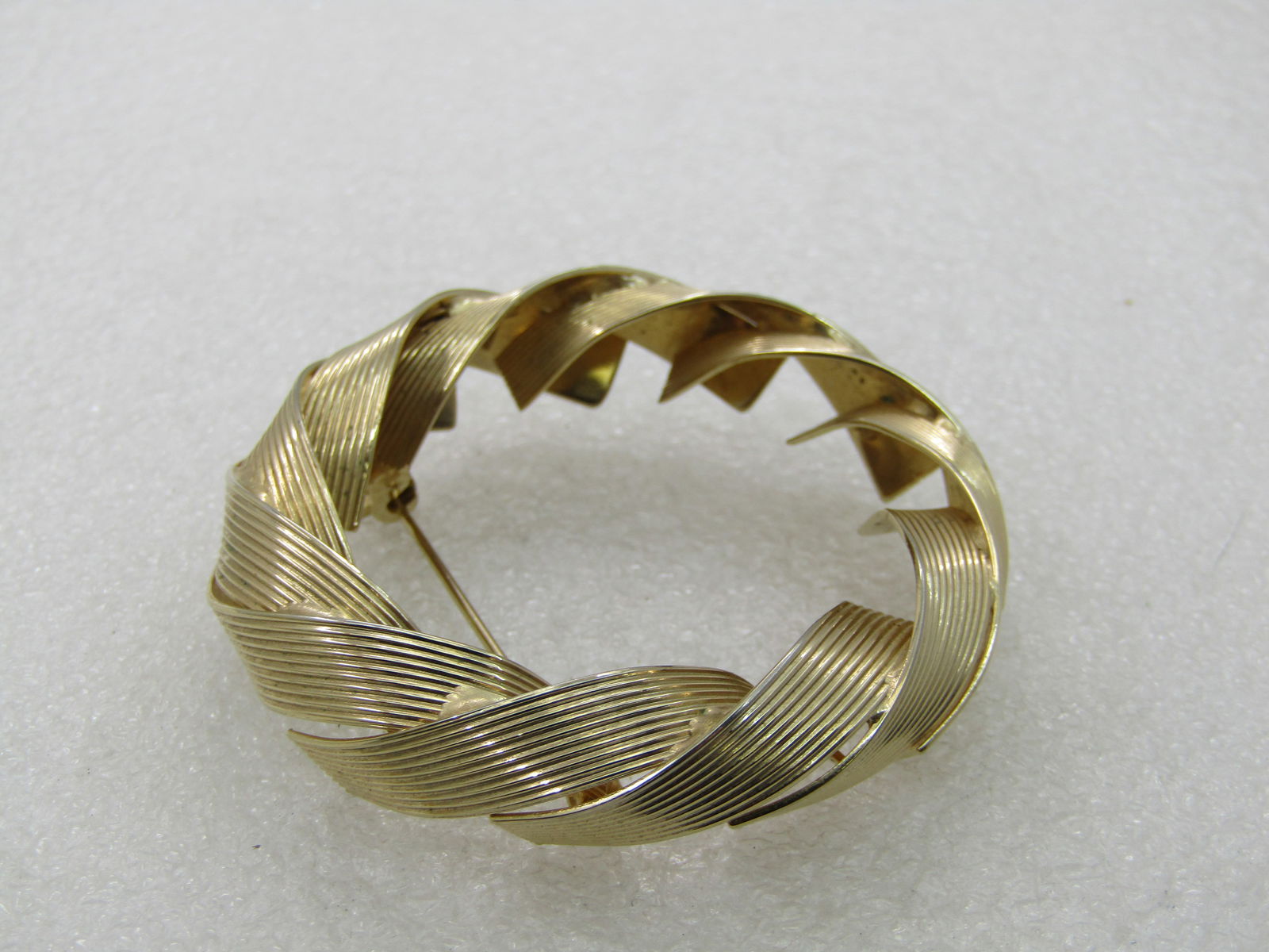Vintage Gold Tone Wrapped Circle Brooch, 2.25" and 10mm wide: Vintage Gold Tone Wrapped Circle Brooch, 2.25" and 10mm wide. The circle is made up of ridged ribbon like wrapped design to creat the circle. Age is appx. 1960's-1970's. It is not signed by the maker.