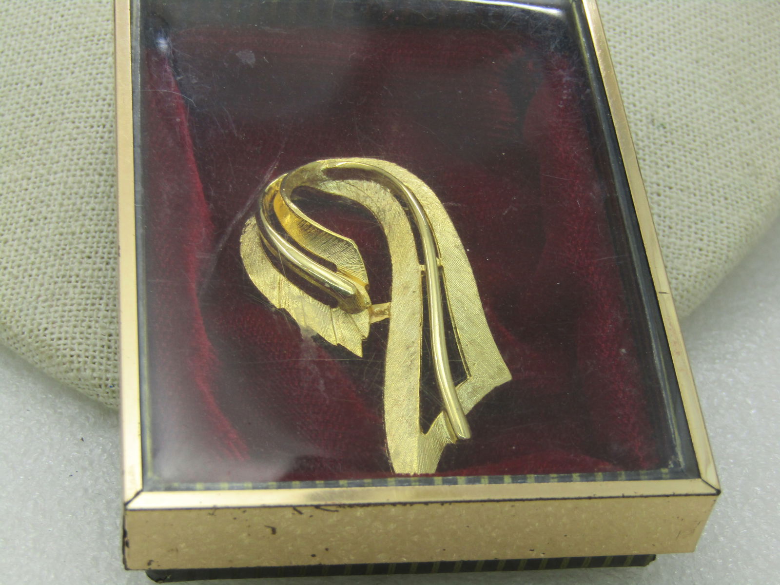 Vintage Gold tone Looped Bow Brooch, Original Box: Vintage Gold tone Looped Bow Brooch, Original Box with red velvet. Textured surface on outer edges with a raised smooth edge, 1960's modern, 2" by 1". Very good condition. Not signed by the maker.