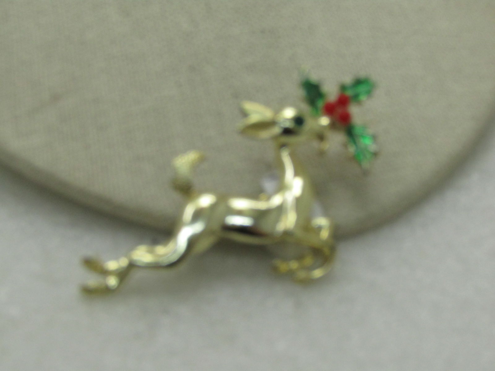 Vintage Reindeer Holly Christmas Brooch, Enameled, 2.5": Vintage Reindeer Holly Christmas Brooch, Enameled, 2.5" and 1.5" tall. Gold tone with green rhinestone eye. Textured and Smooth finish. (INV.W.1.2514.3) Reserve: $15.00 Shipping:Domestic: Flat-rate