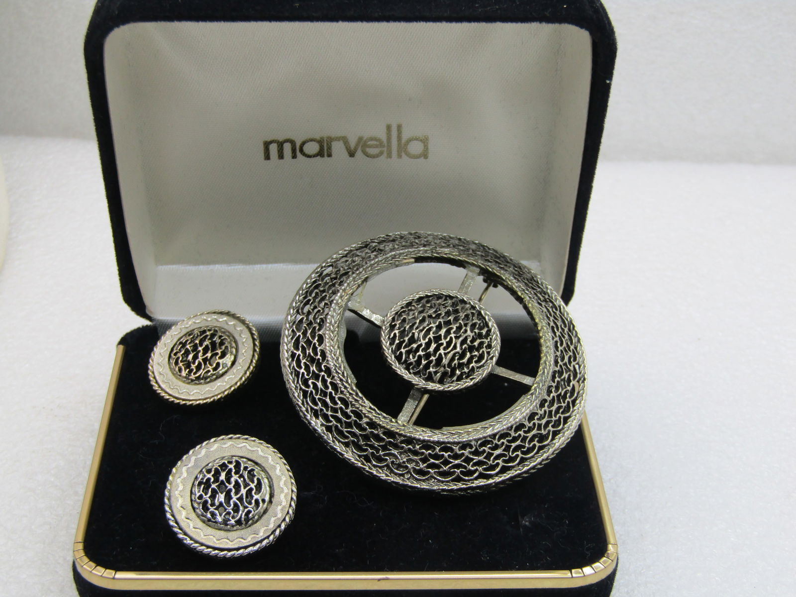 Vintage Marvella Brooch & Clip Earrings Set, in original box: Vintage Marvella Brooch & Clip Earrings Set, in original box which is signed Marvella on the lid. The brooch is appx. 2-3/8" across and has a woven frame angled frame with an open center with bars tha
