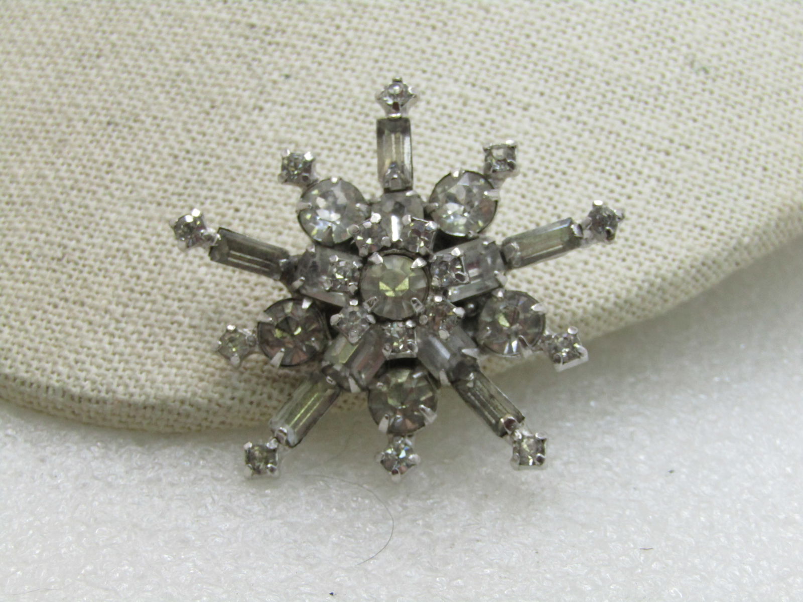 Vintage Clear Rhinestone Snowflake Brooch, 1-3/4", Signed: Vintage Clear Rhinestone Snowflake Brooch, 1-3/4", Signed. You cannot read the maker's mark. The pinback was resoldered and they are covering the center of the wording. 696 is marked on the pinback mo
