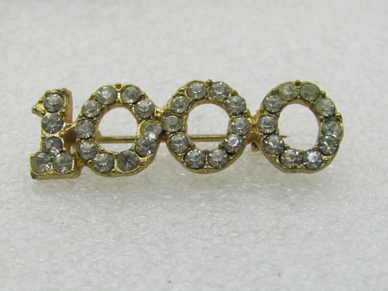Vintage Rhinestone 1000 Brooch, 1.5": Vintage Rhinestone 1000 Brooch, 1.5" wide and 1/2" tall. A milestone pin that can be used for many circumstances - sales goals, points scored, etc. Not sure of the original purpose. It is gold tone