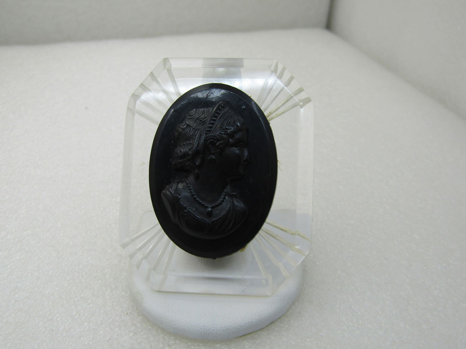 Vintage 1940's Clear Lucite & Black Cameo Brooch, Reverse Carved Frame, 2.5": Vintage 1940's Clear Lucite & Black Cameo Brooch, Reverse Carved Frame, 2.5" by 2". Beveled edge with five rays at each corner cut in the back. The cameo is black oval molded plastic. The cameo is 1-7