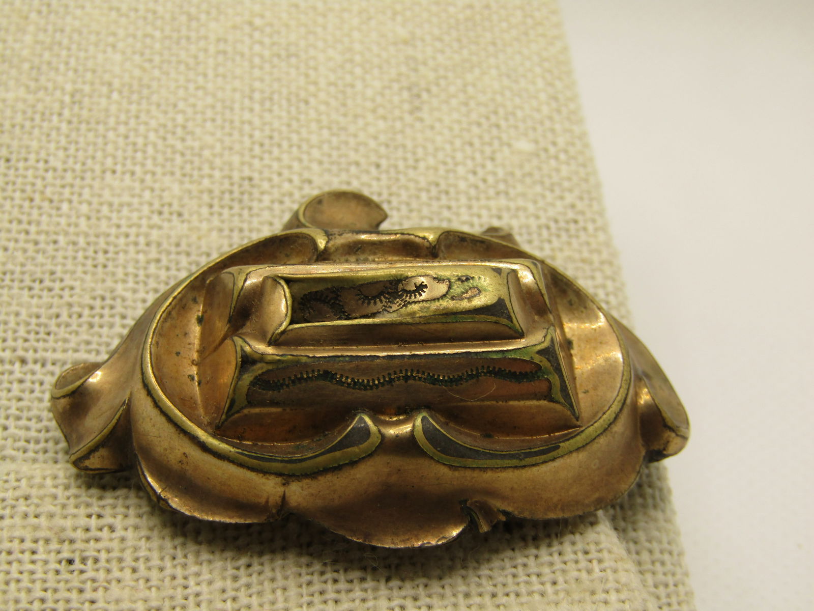 Victorian Raised Brooch, C-Clasp, Damaged on Top. 2": Victorian Raised Brooch, C-Clasp, Damaged on Top. 2" wide and 1-3/8" tall. Tests as 10kt G.F. Scrolled frame with a center raised tiered rectangular accent - unfortunately this is a hollow piece and t