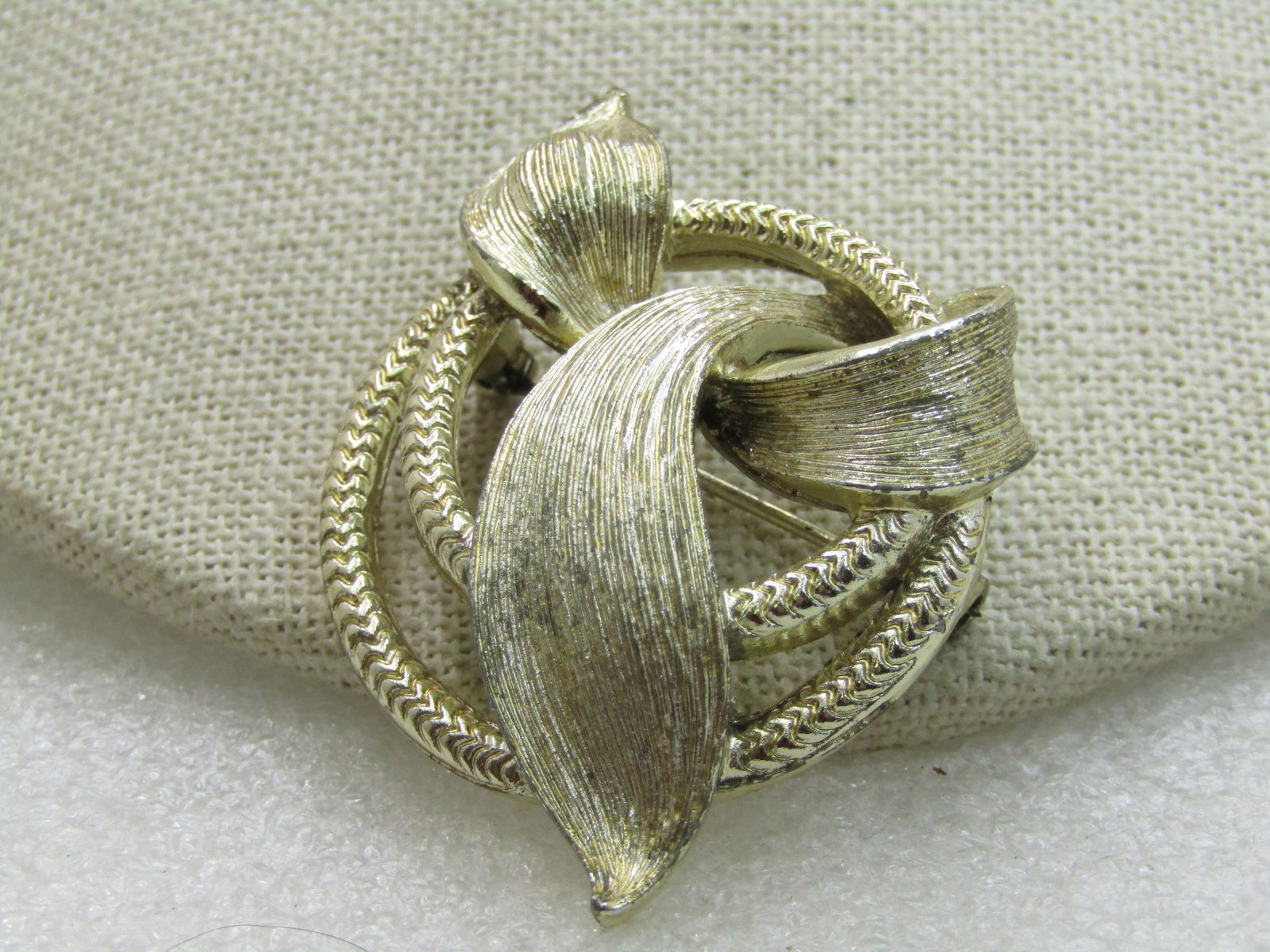 Vintage Lisner Cirle & Wrapped Brooch, Gold Tone, 2": Vintage Lisner Cirle & Wrapped Brooch, Gold Tone, 2" by 1.5". Two concentri textured circles and a textured wrapped accent that curves through the circles. 1960's. Signed Lisner. Very good condition.