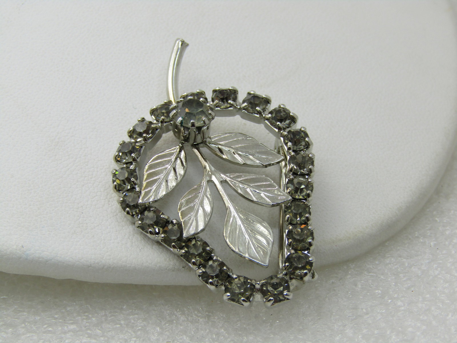 Vintage Rhinestone Pear-Shaped Brooch with Leaves, 1960's, Silver tone, 2": Vintage Rhinestone Pear-Shaped Brooch with Leaves, 1960's, Silver tone, 2". The brooch is framed in smoky rhinestones with a larger stone at the base of the leaves inside the frame. The brooch is 2" t