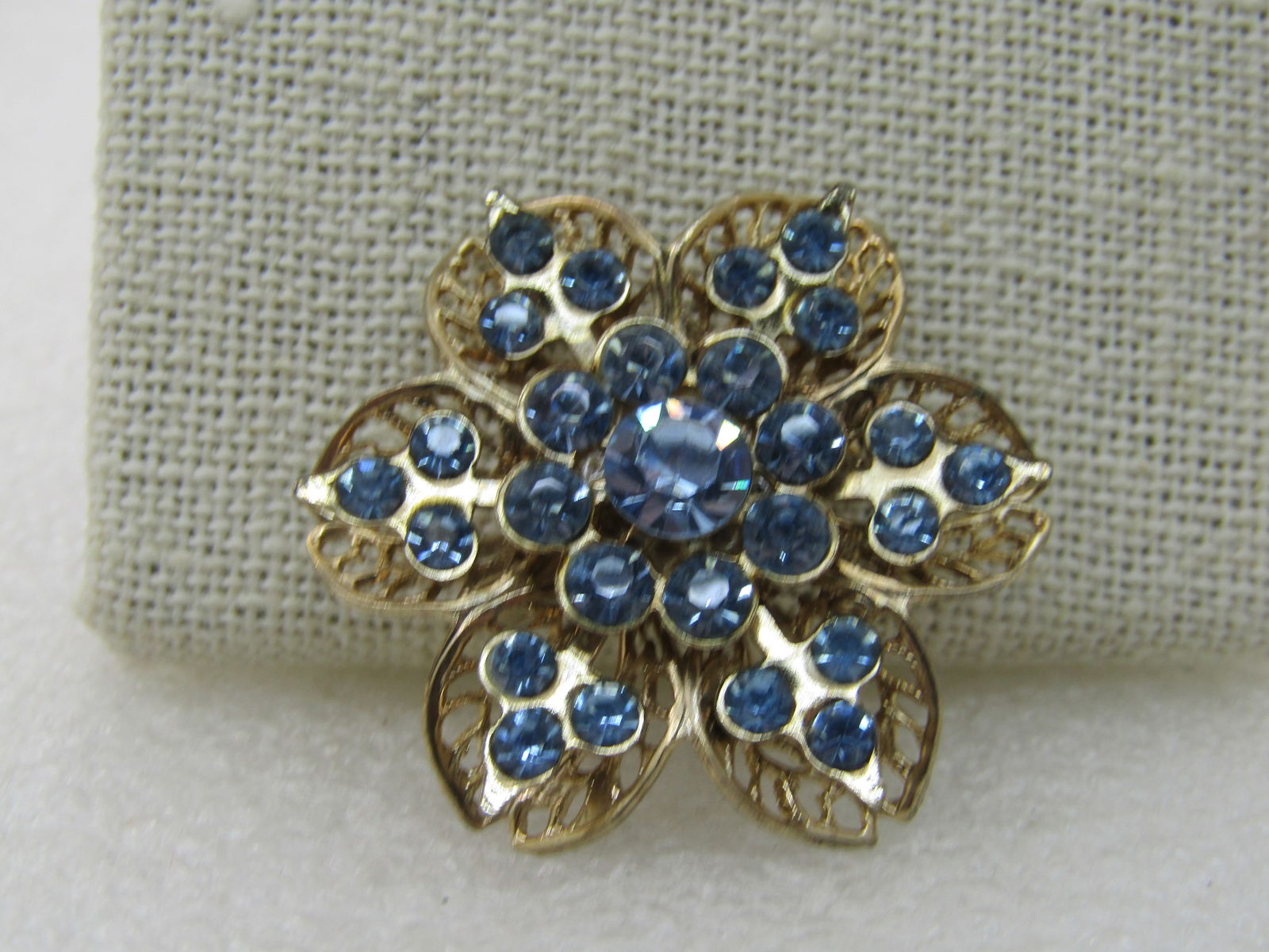 Vintage Blue Tiered Blossom Brooch, Filigree, 1950's-1960's: Vintage Blue Tiered Blossom Brooch, Filigree, 1950's-1960's, Gold tone with baby blue stones in the second and center tiers. The bottom tiers are curved filigee petals. The middle layers has pointed p