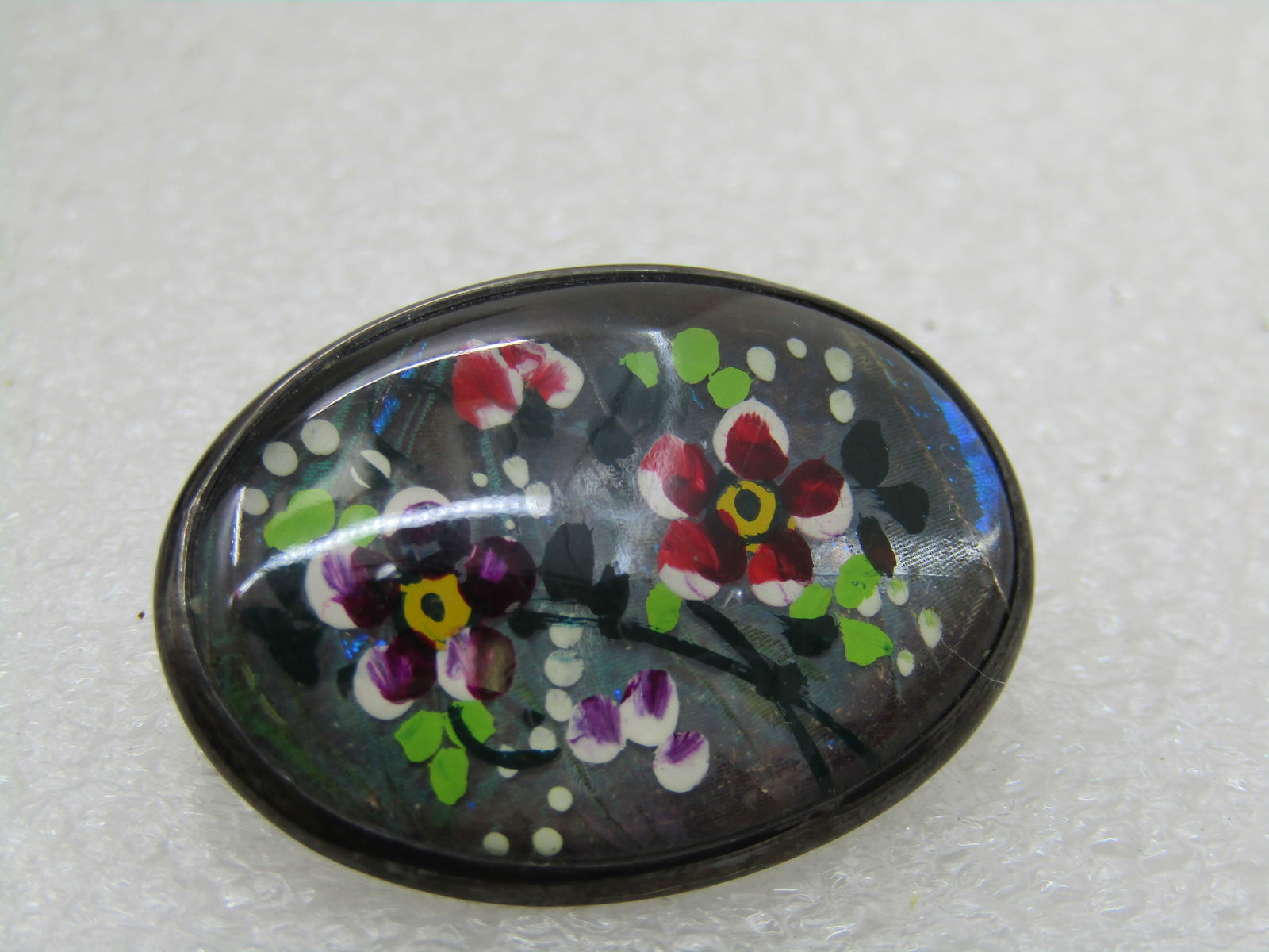 Vintage Sterling Reverse Painted Floral Brooch, 1940's: Vintage Sterling Reverse Painted Floral Brooch, 1940's, 1.25" wide and 1" tall oval glass painted with purple, red flowers and green leaves and white dotted accents. The pin extends beyond the clasp.