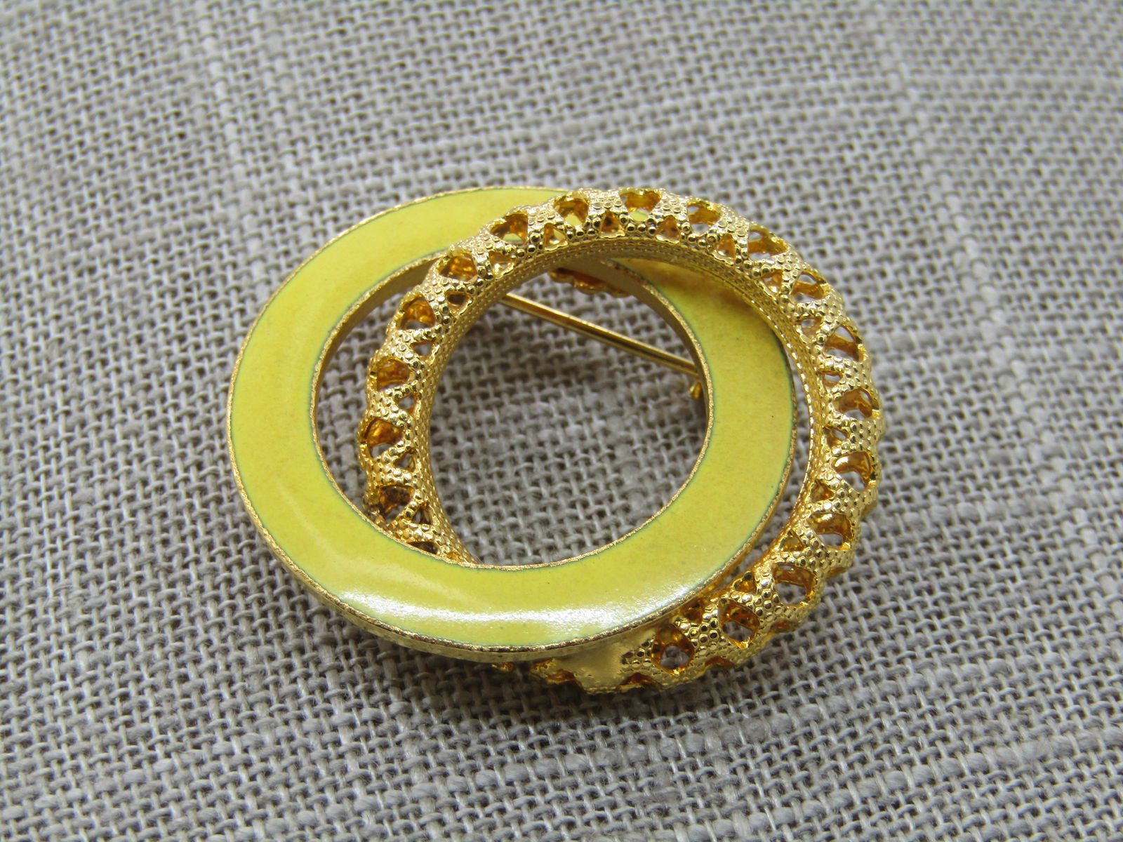 Vintage Yellow Enameled Filigree Circle Brooch, 1.25": Vintage Yellow Enameled Filigree Circle Brooch, 1.25"with a yellow nearly 5mm circle with an interlocking 3.8mm filigree gold tone circle. Very good condition. 1960's-1970's. Not signed by the maker.
