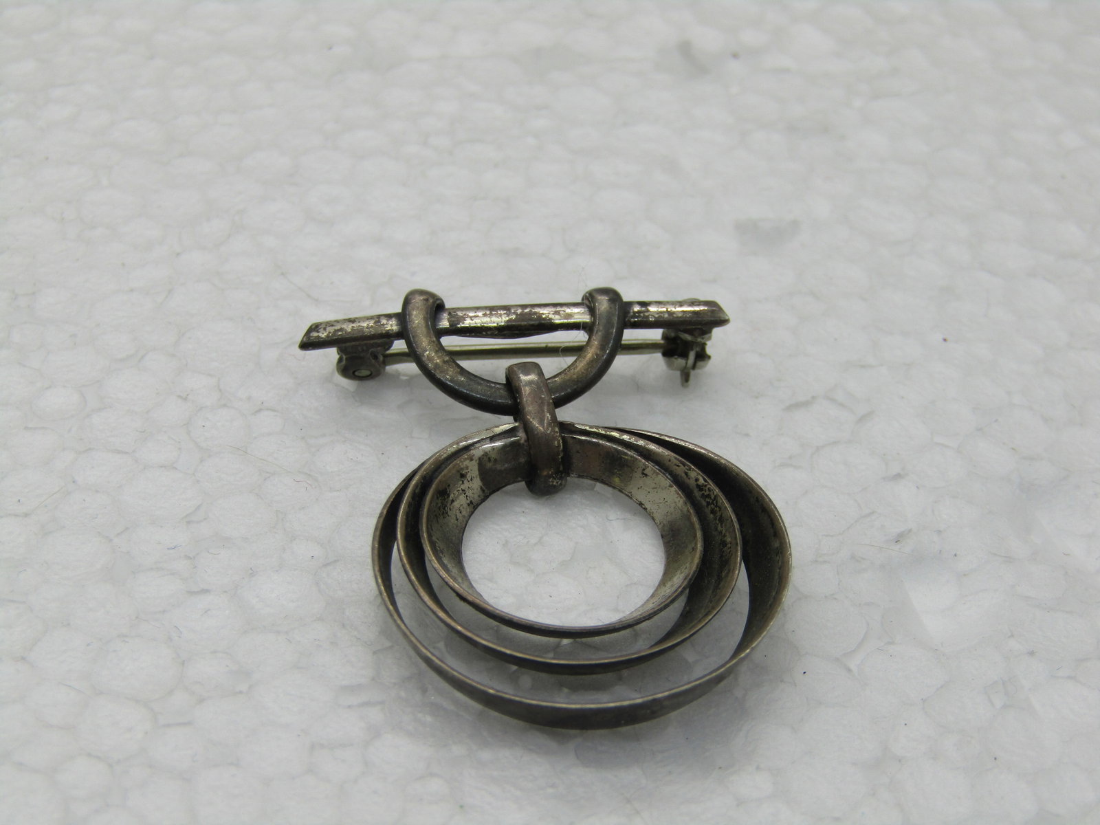 Vintage Sterling Bar & Circle Brooch, 1920's-1940's, 4.64 gr.: Vintage Sterling Bar & Circle Brooch, 1920's-1940's, 4.64 gr. This has a bar with a loop from which a triple concentric circle drops, tapered. The brooch is 1.25" long nad 1" wide. It is marked sterli