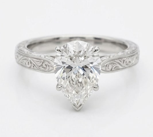 Solitaire with Hand Engraved Scroll Shank Pear Shape 4 ct Lab-Grown Diamond Ring in 14K White Gold: Title: Solitaire with Hand Engraved Scroll Shank Pear Shape 4 ct Lab-Grown Diamond Ring in 14K White Gold Description: This refined solitaire with hand engraved scroll shank ring features a 4 ct lab-g