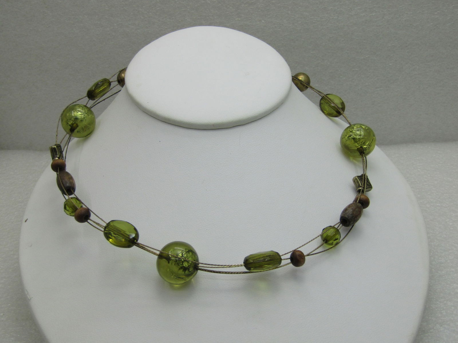 Vintage Four Strand Beaded Necklace 22": Vintage Four Strand Beaded Necklace, 18" and 4" extender. Strung on gold tone textured wire. Green beads with foiled center, wooden beads and brass colored beads. Circa 1980's. Good condition. Light w