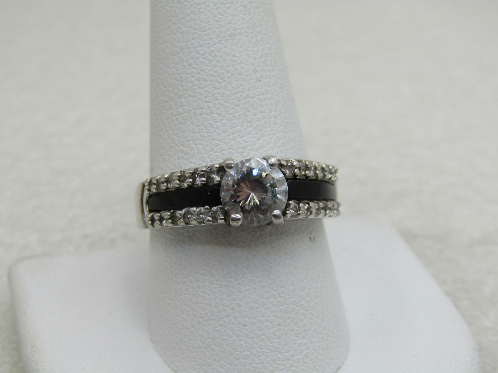 Silver Plated CZ Black & Clear Ring, Sz. 10.5. Tiered, 3 Rows: Silver Plated CZ Black & Clear Ring, Sz. 10.5. Tiered, 3 Rows. Main clear CZ is appx. 6.5mm round cut. The ring is appx. 7.5mm down the finger at top and tapers to appx. 3.5mm at the back of the finge