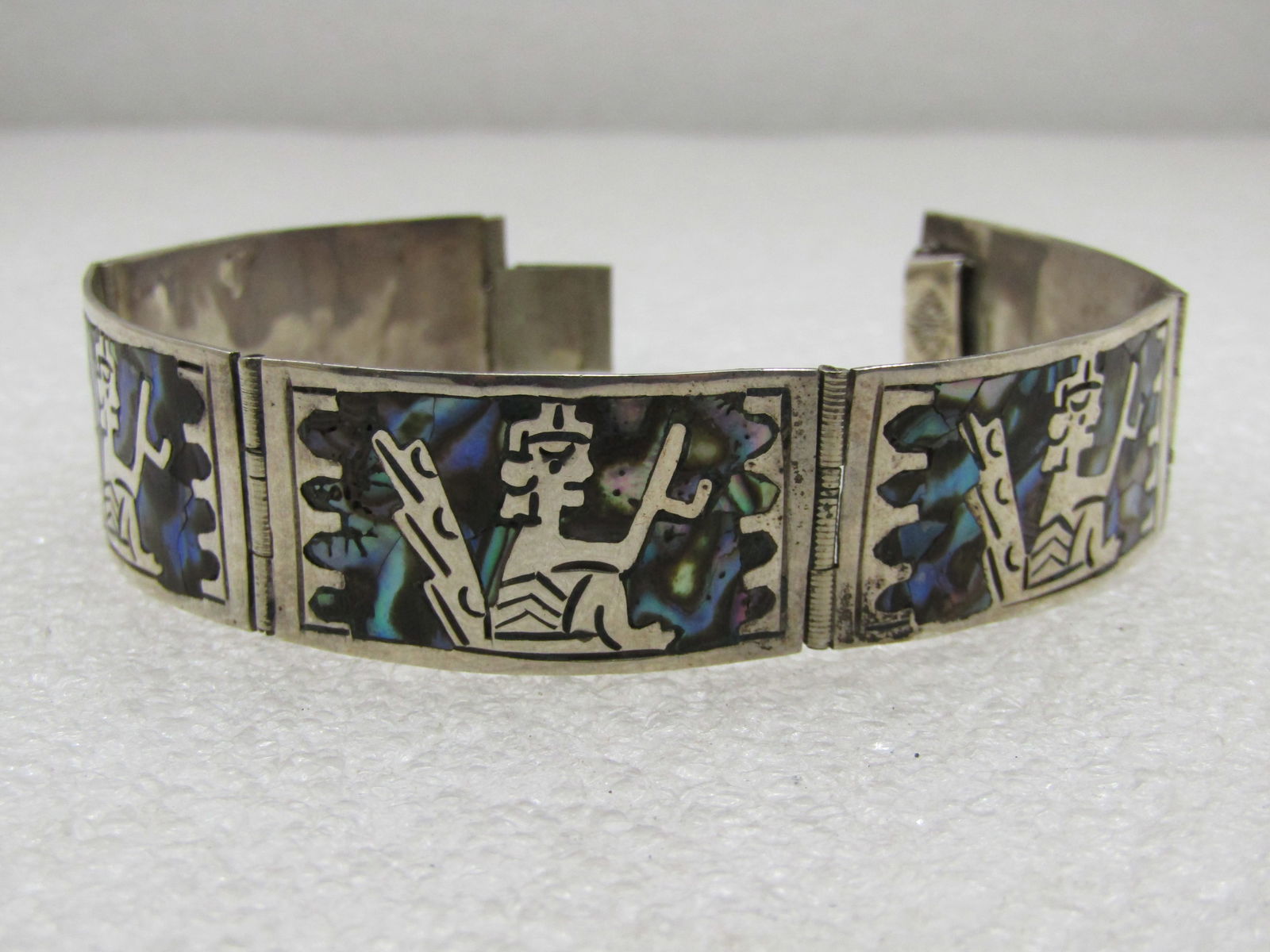 Vintage Mexican Sterling Inlaid Aztec Abalone Bracelet, 7" 1950's-1960's: Vintage Mexican Sterling Inlaid Aztec Abalone Bracelet, 7" 1950's-1960's, marked sterling and appx. 18.14 gr. It is 3/4" wide and made with fived curved panels each with the same figure and scallope i