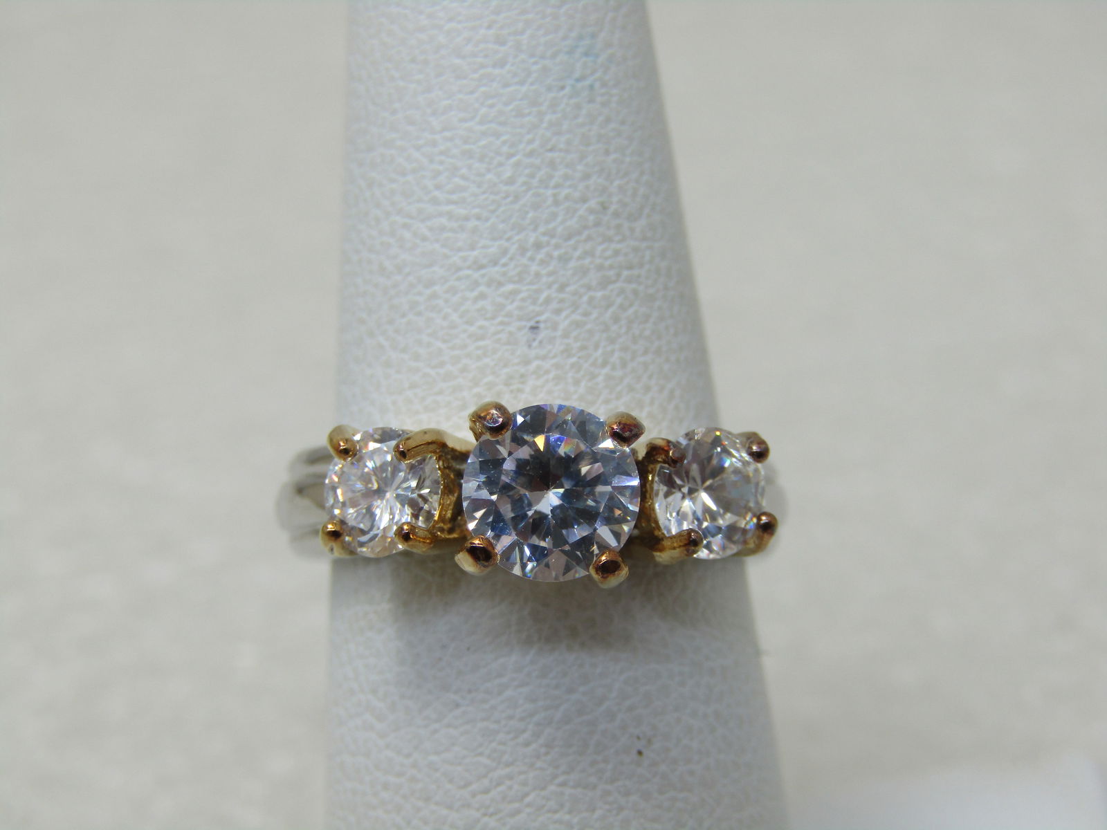 Lind Silver Plated Triple CZ Ring, Two-Tone, Sz. 7.25: Lind Silver Plated Triple CZ Ring, Two-Tone, Sz. 7.25 The center stone is larger and equivalent to 1CT with two 1/2 carat CZ, one on each side. Silver Plated Band with gold tone prongs. Striking ring