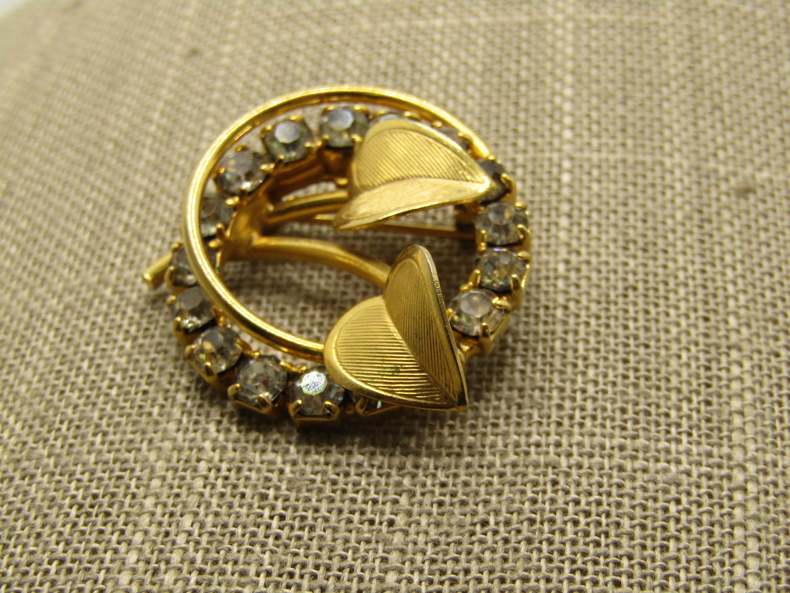 Vintage Clear Rhinestone Leaf Circle Brooch, 1960's: Vintage Clear Rhinestone Leaf Circle Brooch, 1960's, Gold tone with two hear-shaped textured leaves that have angled design and a double circle, one clear rhinestones and the other a round smaller rou