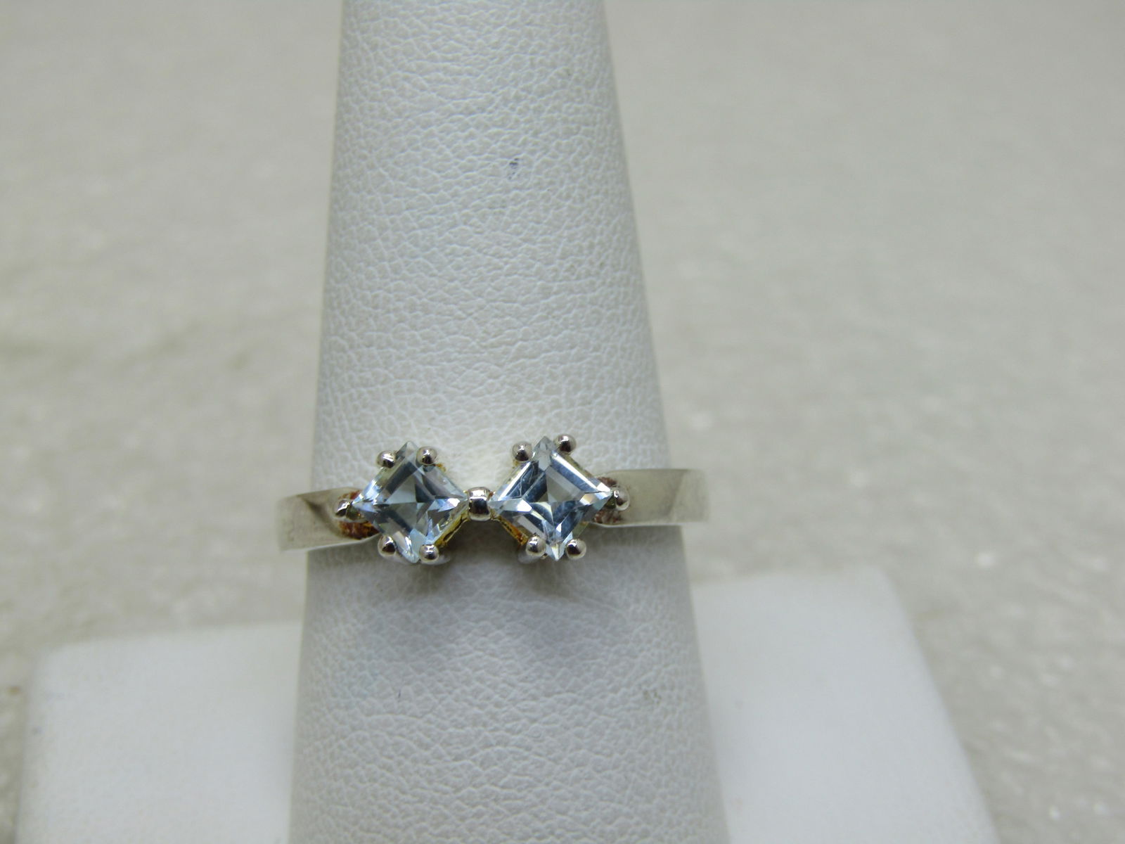 Rhodium Plated Blue Topaz Ring, Sz. 9.5, 2.81 gr.: Rhodium Plated Blue Topaz Ring, Sz. 9.5, 2.81 gr. , marked .925 and signed with a triangular mark. Two square light blue topaz stones, set on the corners, 4.5mm. The ring is appx. 5.6mm at top center