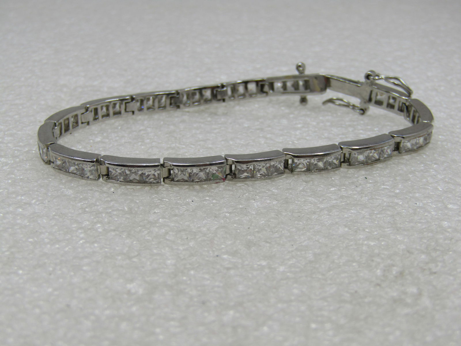 Silver/Rhodium Plated CZ Tennis Bracelet, 7", 4.5mm wide: Silver/Rhodium Plated CZ Tennis Bracelet, 7", 4.5mm wide Channel set CZ crystals in a domed link - 16 links with three sones in each accwept for the one at the clasp. Appx. 4.5mm wide. Box clasp with