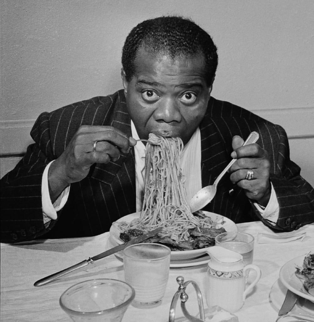 Slim Aarons Official Estate Print - Dinner Jazz: 1949 (Printed later): Title: Slim Aarons Official Estate Print - Dinner Jazz: 1949 (Printed later) Description: Dinner Jazz American Jazz trumpeter and singer Louis Armstrong enjoys a plate of spaghetti in Rome. Paper size