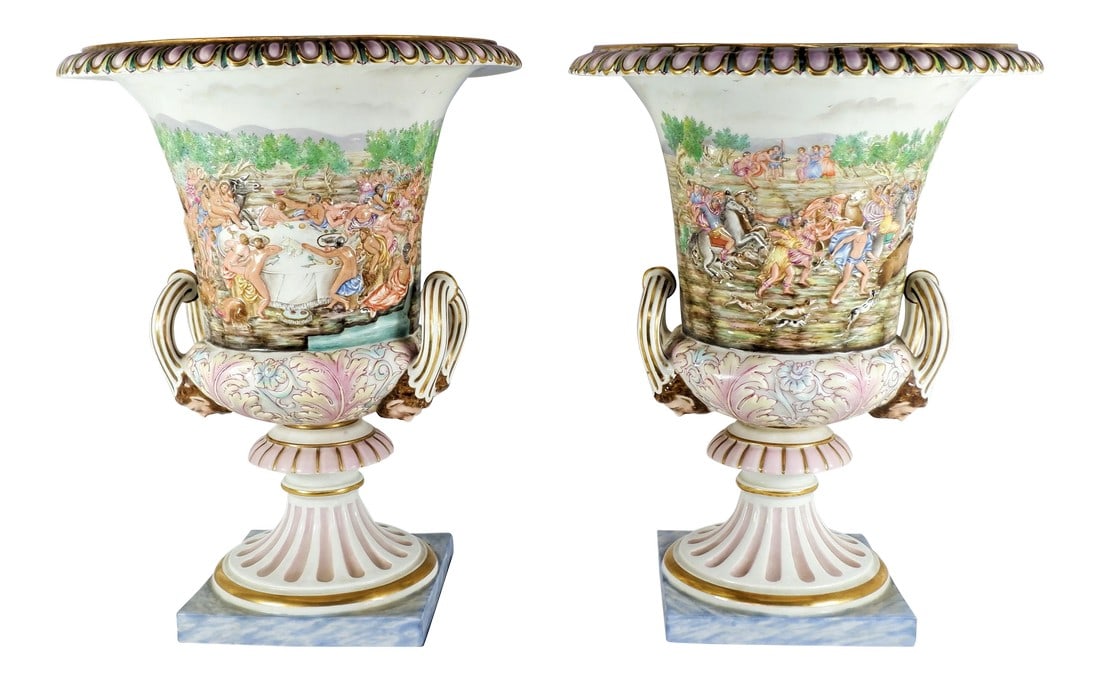 Mid 19th Century Antique Ginori Capodimonte Urns - a Pair: An antique pair of 19th century Ginori Capodimonte urns. Reliefs on the side depict nude and clothed people dancing and eating. There is also a snake and half beast man. At the bottom of side handles