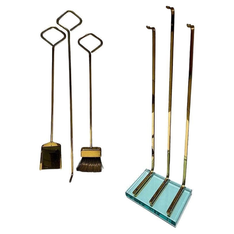 Italian Modernist Brass and Glass Fireplace by Fontana Arte: Elegant modern fireplace tool set by Fontana Arte, circa 1970’s. The set includes a shovel, poker, and broom. Original brass bristles on a broom. The set is forged in brass, with each handle fit