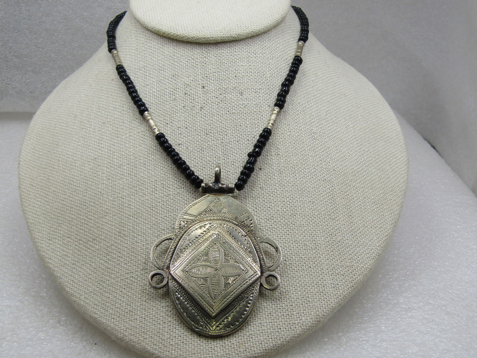 Vintage Mid-Eastern Themed Necklace, Etched Pendant, Black Beaded 18": Vintage Mid-Eastern Themed Necklace, Etched Pendant, Black Beaded 18". This has a 2.75" pendant that is tiered with engraved or etched design and almost has the look of a face or mast with scrolls on