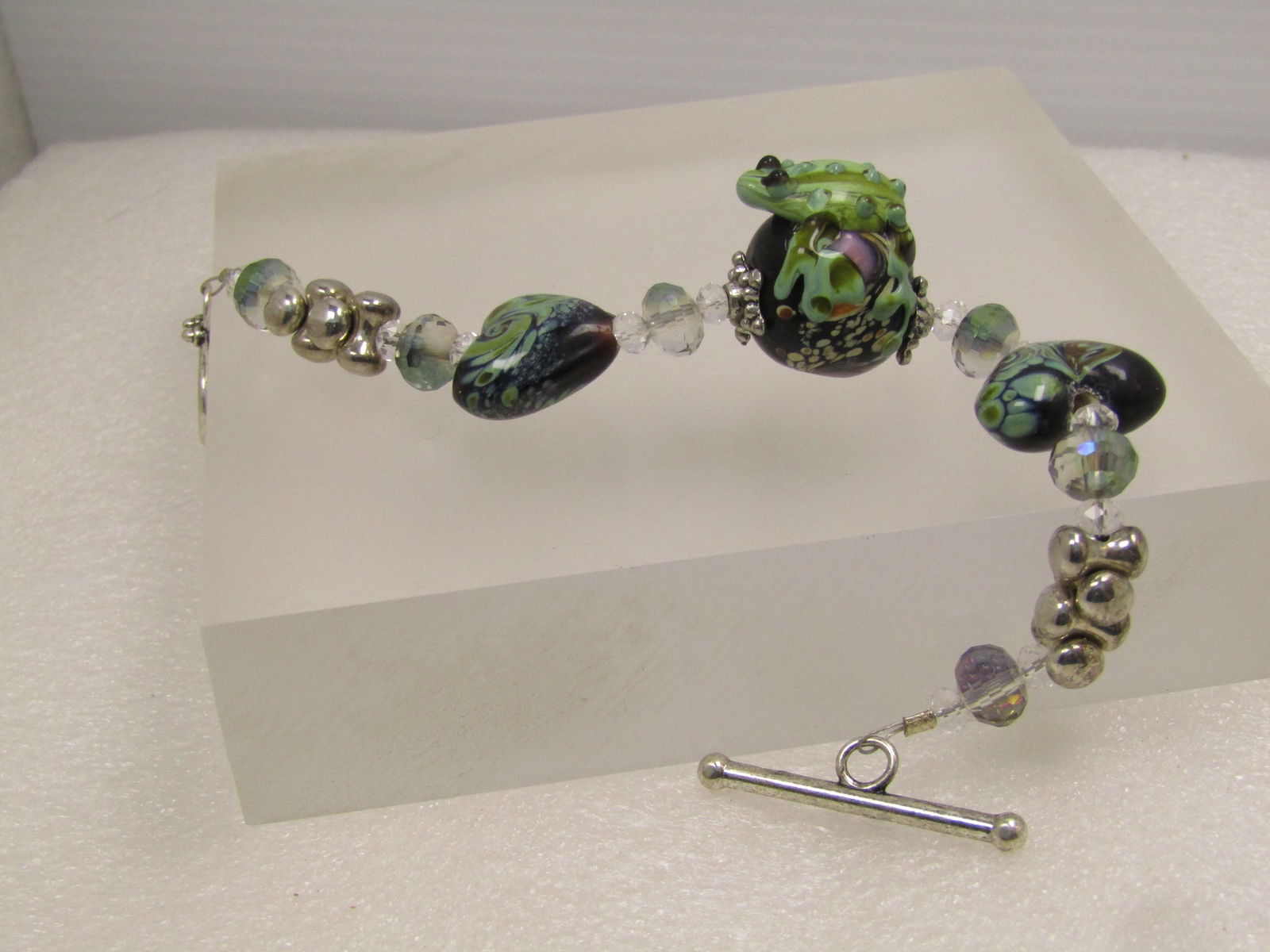 Vintage Brown/Green Art Glass Bracelet, Heart/Frog, Toggle Clasp, 7.25", 1990's: Vintage Brown/Green Art Glass Bracelet, Heart/Frog, Toggle Clasp, 7.25", 1990's. This has a center brown glass bead with a glass frog placed on the top side and pink, orange and white with some green