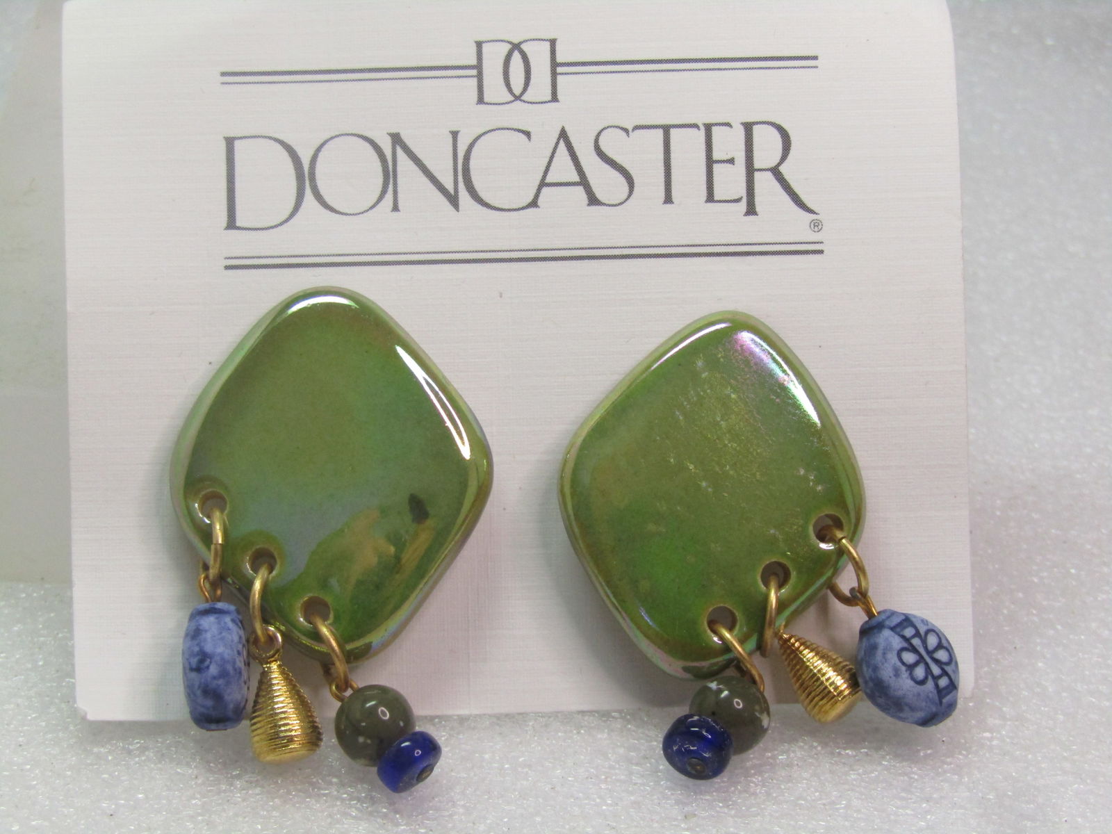 Vintage DonCaster Ceramic Dangling Earrings, Clip, on Card., 1990's: Vintage DonCaster Porcelain Dangling Earrings, Clip, on Card., 1990's. These earrings have a base of a porcelain, or ceramic, iridescent green flat top that is appx. 1.25" tall and 1" wide and a recta