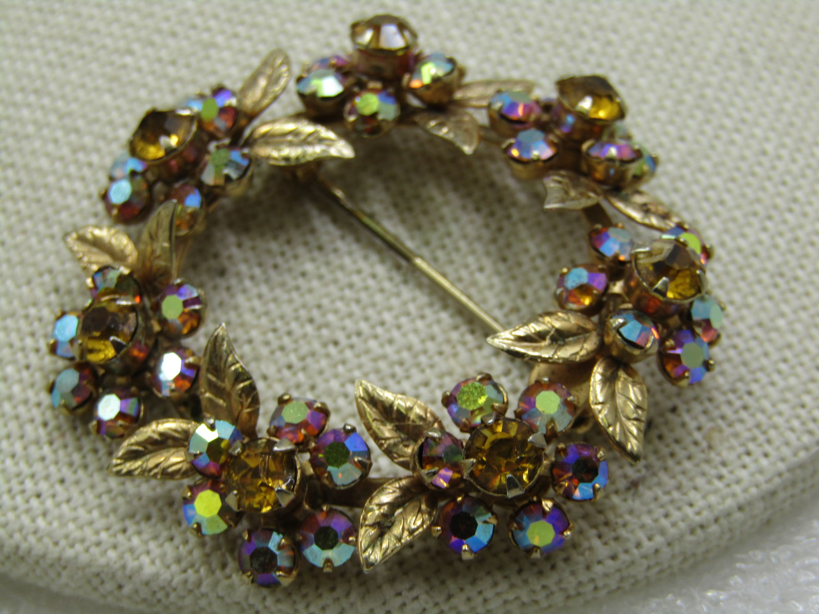Vintage Rhinestone Wreath Brooch, Aurora Borealis Blossom, 1-5/8": Vintage Rhinestone Wreath Brooch, Aurora Borealis Blossom, 1-5/8", mid century boroch with 7 clusters each with a raised purple/pink/blue rhinestone aurora borealis blossom and detailed leaves around
