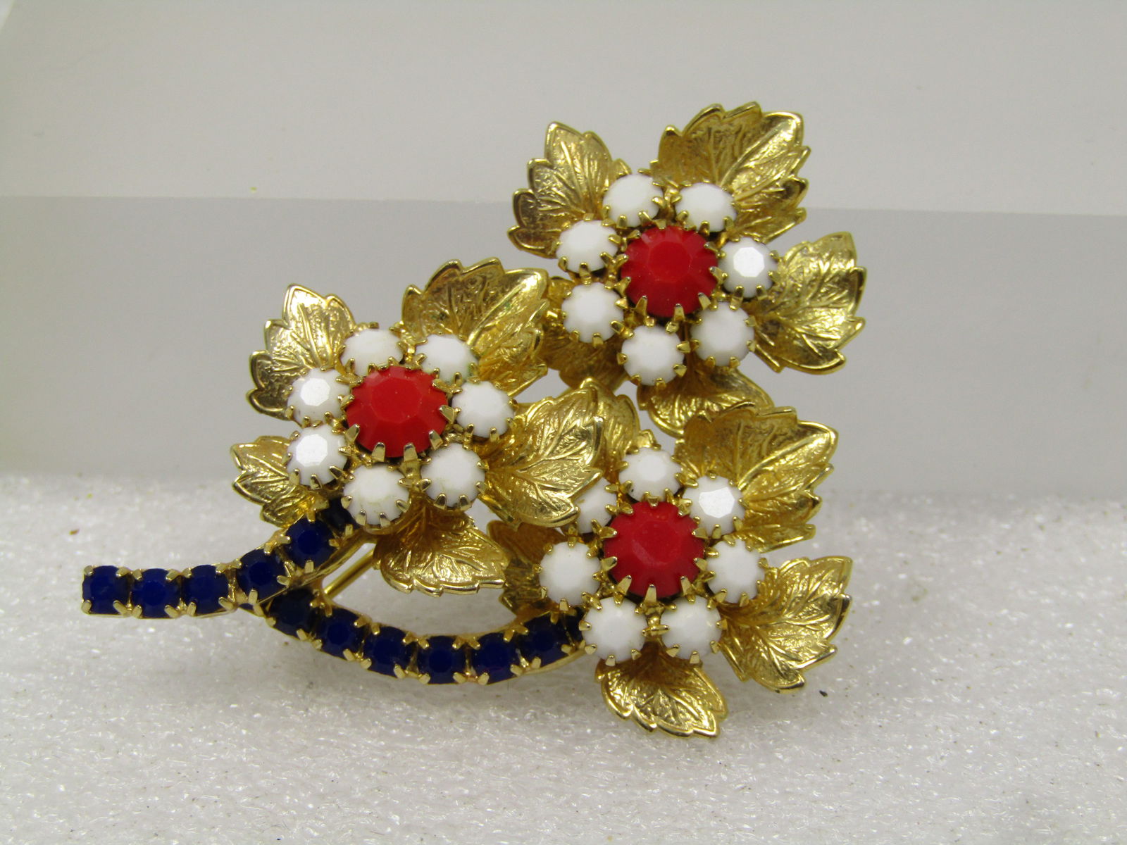 Vintage Red/White/Blue Blossom Stem Brooch, 1960's: Vintage Red/White/Blue Blossom Stem Brooch, 1960's. Great for patriotic holidays too. Gold tone with three blossoms and a center of milk glass w hite and red stones and blue rhinestones as the stems.
