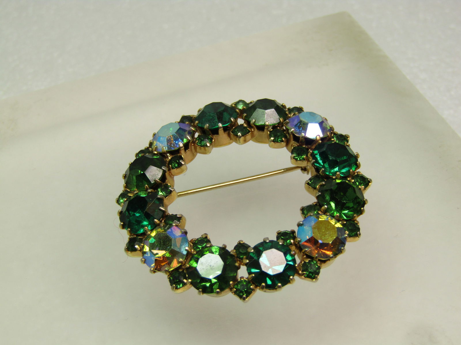 Vintage Green Aurora Borealis Brooch, Signed Karu Arke, 1950's: Vintage Green Aurora Borealis Brooch, Signed Karu Arke, 1950's. Green crystal/glass stones with larger and smaller round stones and four aurora borealis stones. Gold tone, prong-set. Signed Karu Arke.