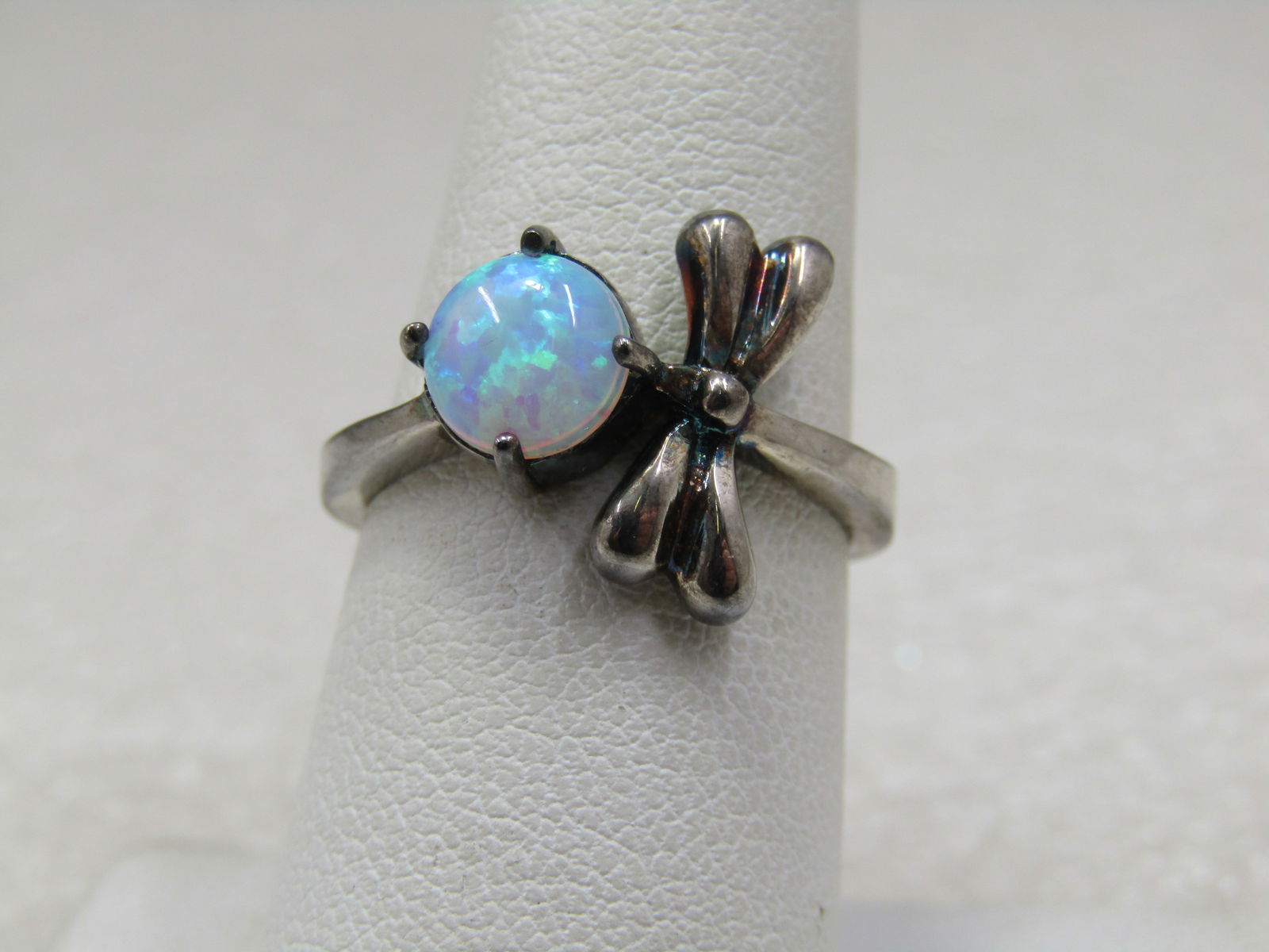 Silver Created Opal Dragonfly Ring. Size 7, marked .925: Silver Created Opal Dragonfly Ring. Size 7, marked .925 but it is not sterling but a silver plating. The dragonfly is facing the firey 7mm round opal and wraps around the finger to the other side of t