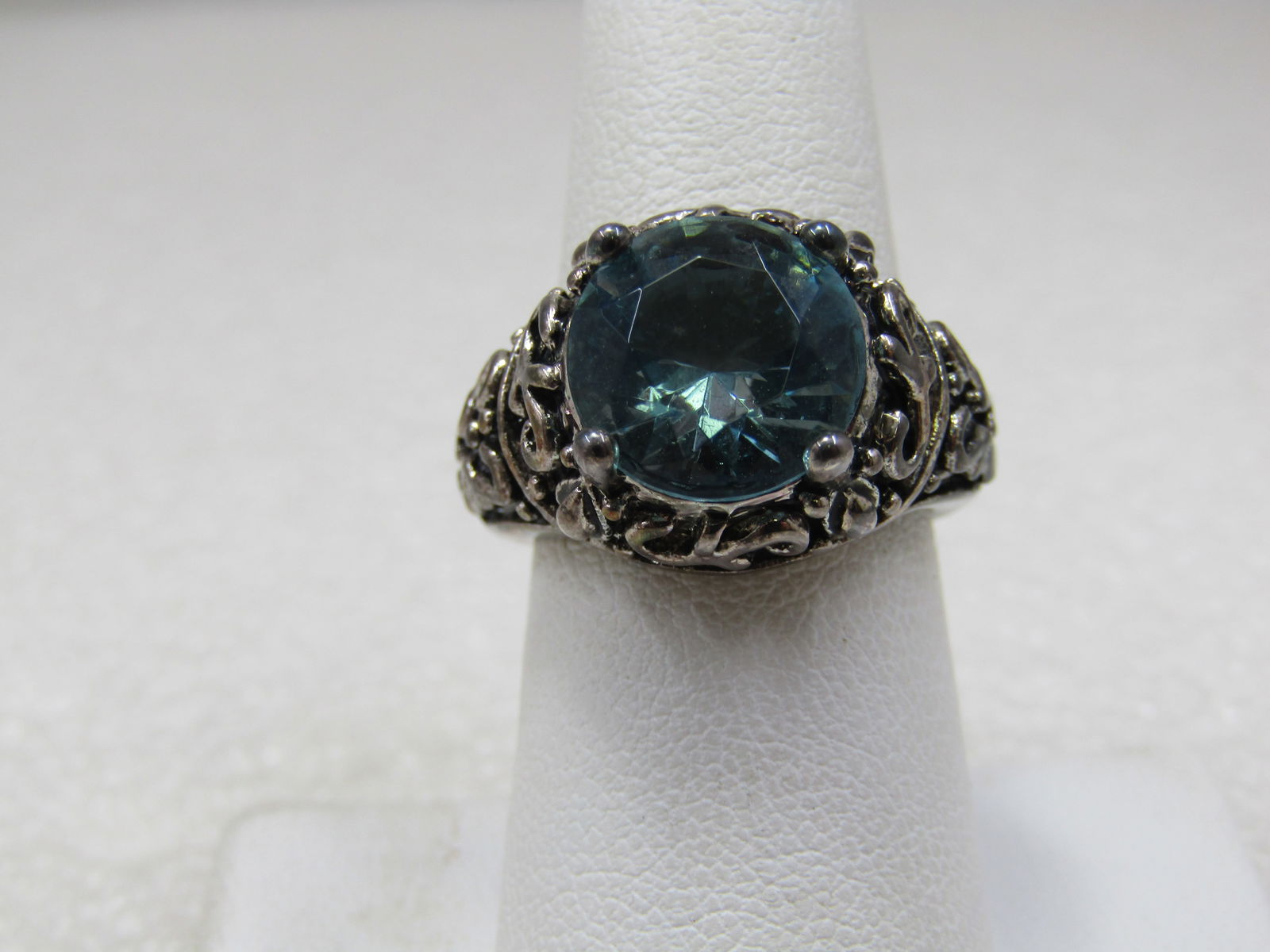 Silver Tone Simulated Blue Topaz Scrolled Ring, Sz. 7, Statement Ring: Silver Tone Simulated Blue Topaz Scrolled Ring, Sz. 7, Statement Ring. This has an appx. 11mm round simulated blue topaz stone with a scrolled design across the top of the ring and down the sides of t