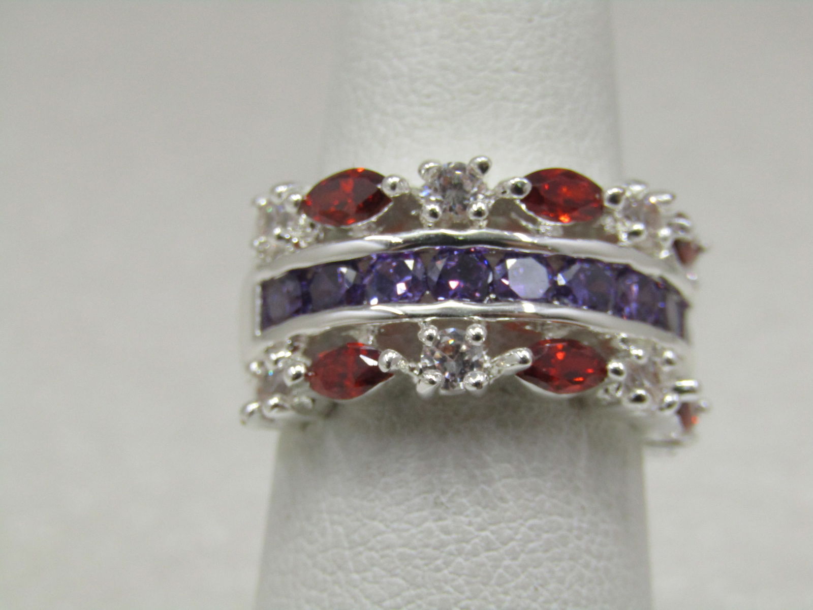 Silver Plated Rhinestone Band Ring, Red/Purple/Clear, Sz. 6.75, Cigar Band: Silver Plated Rhinestone Band Ring, Sz. 6.75, Cigar Band and appx. 10mm wide with a mix of marquise red rhinestones and clear round stones on the outer edges and purple amethyst colored stones