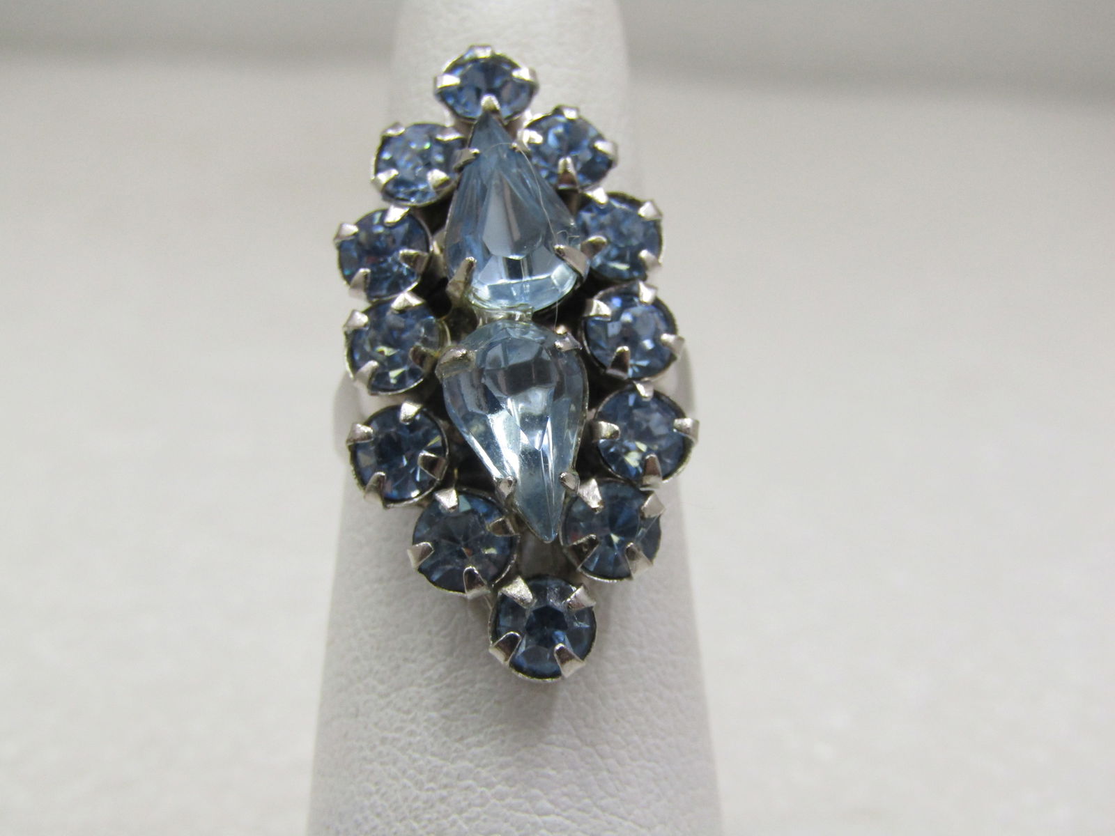 Vintage Blue Rhinestone Ring, Adjustable, Mid-Century: Vintage Blue Rhinestone Ring, Adjustable, Mid-Century, Sz. 5-11. Two 8mm by 6mm pear shaped blue rhinestones in the center, raised slightly higher than the halo of round 4mm stones that are arranged i