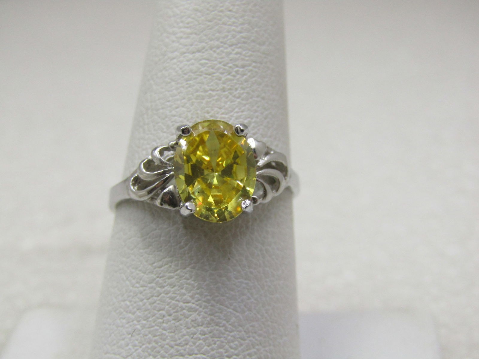 Yellow Stone Scrolled Ring, Sz. 7.75, Silver Tone: Yellow Stone Scrolled Ring, Sz. 7.75, Silver Tone. Appx. 9mm by 7mm oval stone in a scrolled design. This is marked .925 but is not sterling - it is a constume ring, very pretty but costume. It is
