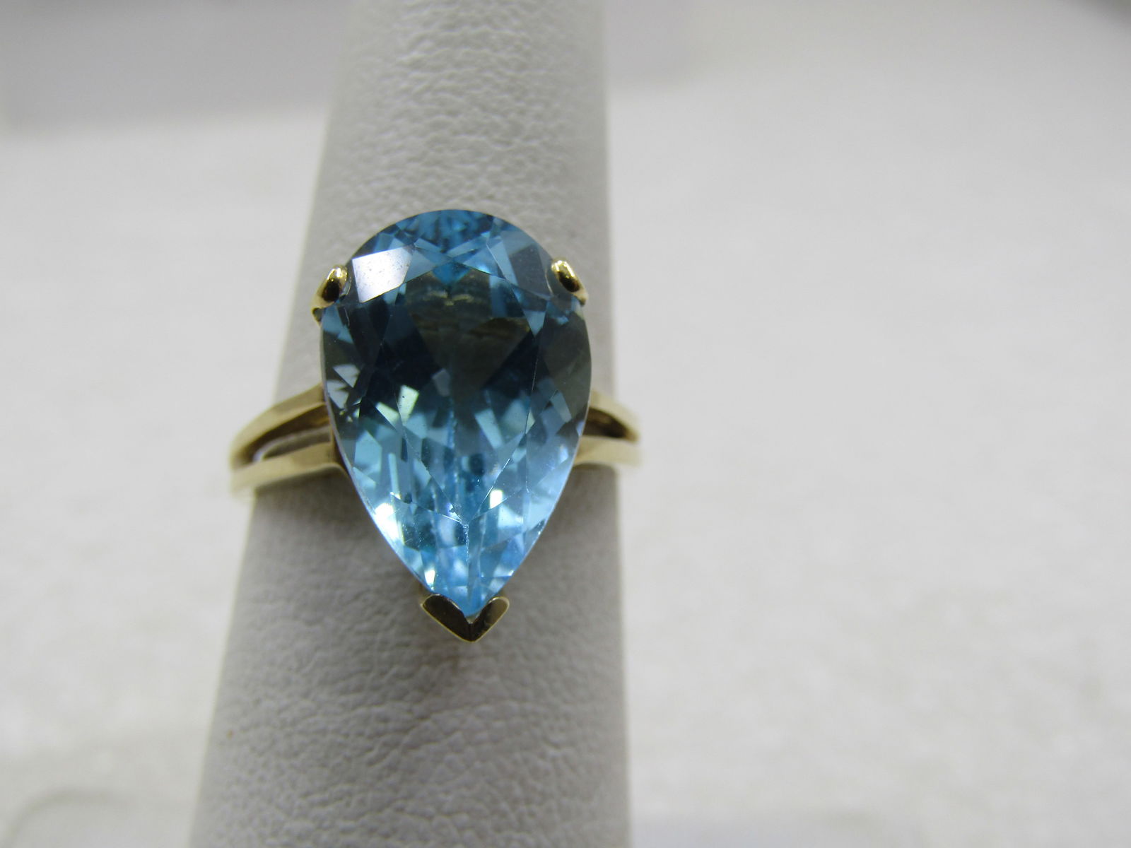 Vintage 10kt Blue Topaz Pear Shaped Ring, Sz. 6, 7.25 tcw, Signed: Vintage 10kt Blue Topaz Pear Shaped Ring, Sz. 6, 7.25 tcw, Signed UNS in a triangular frame. It is marked 10kt and isyellow gold with a weight of appx. 3.60 grams. It has an open double band look at t