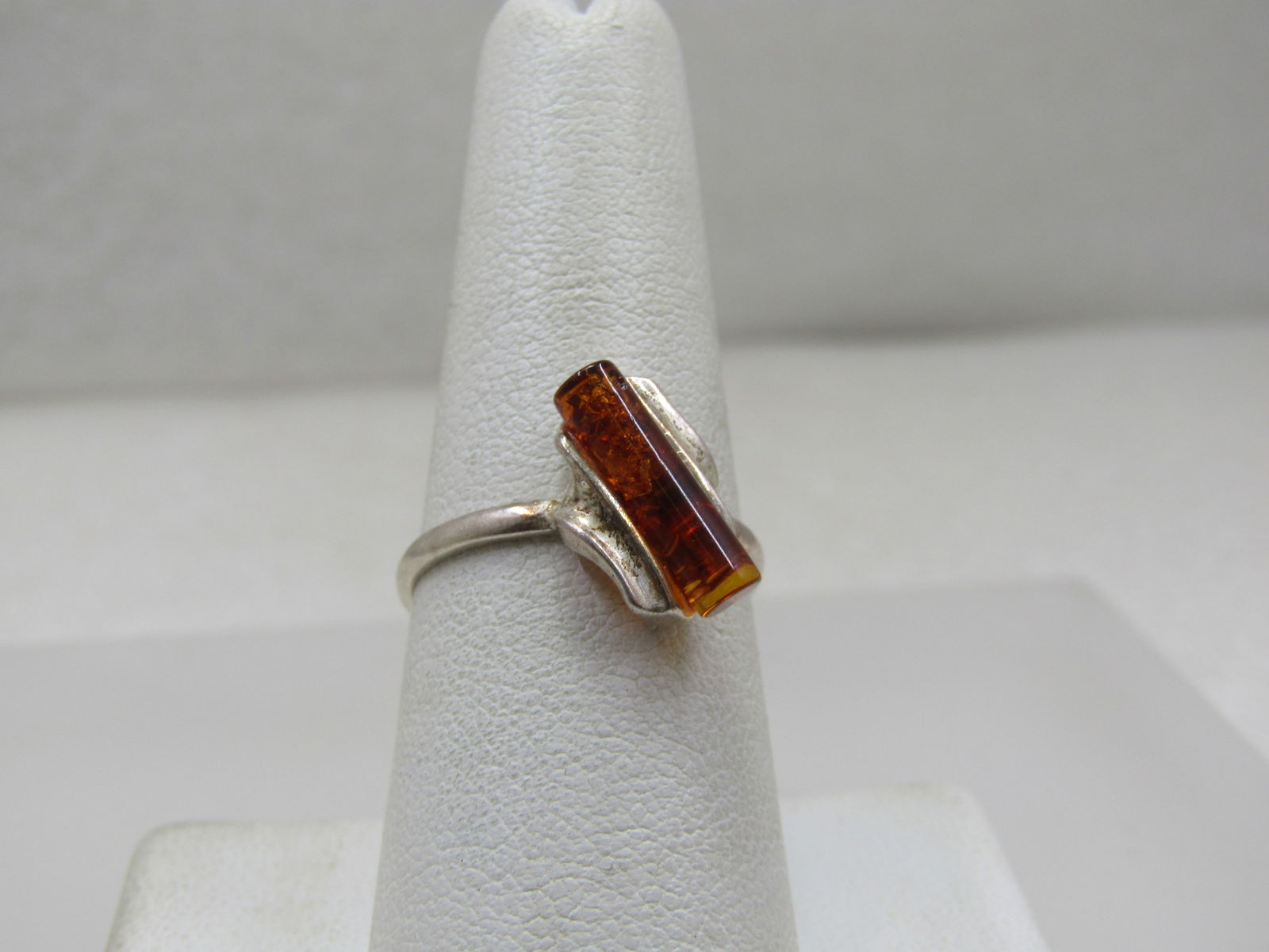 Sterling Silver Amber Tubular Ring, Sz. 8: Sterling Silver Amber Tubular Ring, Sz. 8. This has a round tubual amber piece that is appx. 13mm by 3.5mm set at an angle with a bypass design of surved sterling sides. The top of the ring is apx. 13