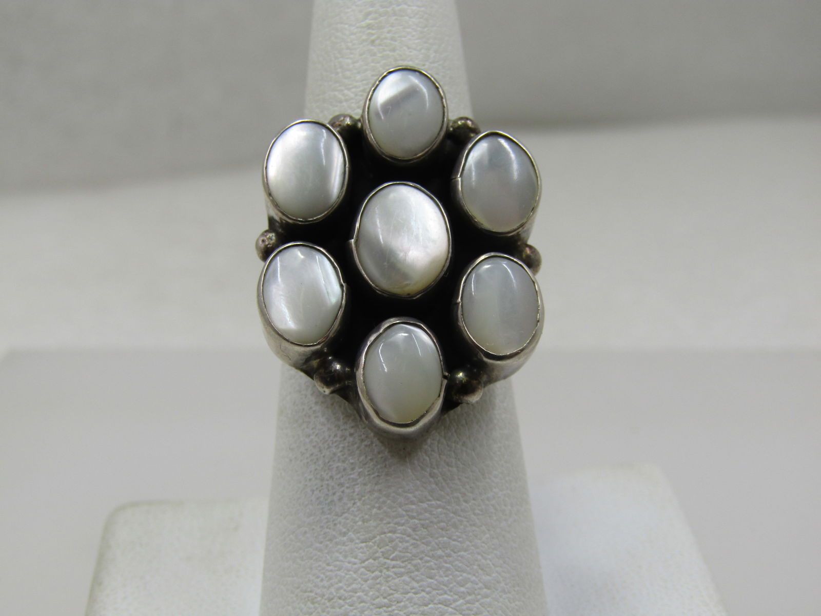Vintage Sterling Southwestern Mother-of-Pearl, Ring, Cluster, Sz 7. Signed H: Vintage Sterling Southwestern Mother-of-Pearl, Ring, Cluster, Sz 7. Signed H. This is a cluster/blossom design with six bezel-set mother-of-pearl oval stones and an additional one in the center. They