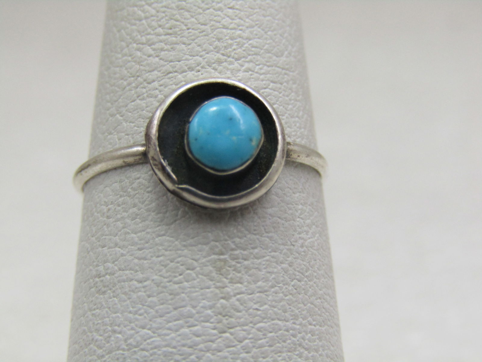 Vintage Sterling Southwestern Turquoise Ring, Sz. 5.75: Vintage Sterling Southwestern Turquoise Ring, Sz. 5.75. This has a round shadowbox design with an appx. 4.5mm bezel-set turquoise in center set over a black backround that is recessed and lower than t