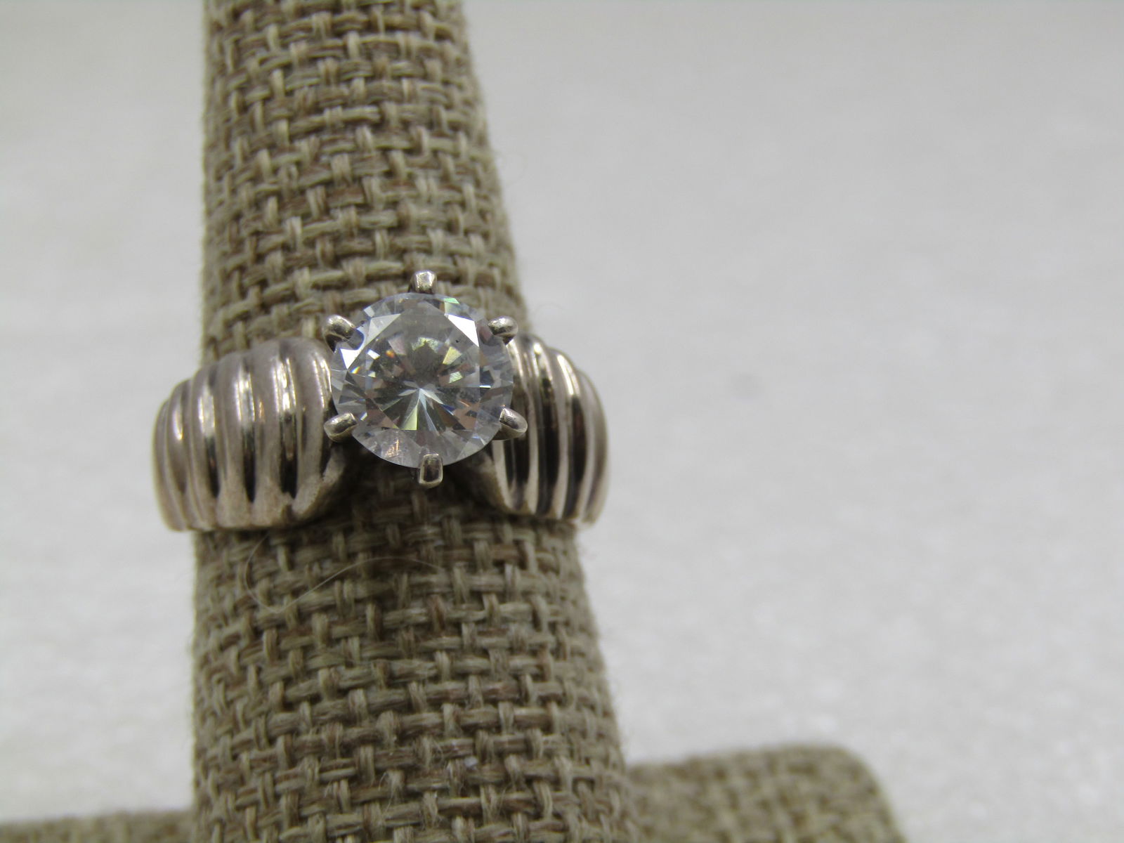 Vintage Sterling CZ Engagement Ring, Sz. 8, 2 CTW, Signed Diamonique: Vintage Sterling CZ Engagement Ring, Sz. 8, 2 CTW, Signed Diamonique. Wide ridged band at appx. 8.5mm wide that tapers down to appx. 3mm at back of the finger. The ridges ar on the top of the shoulder