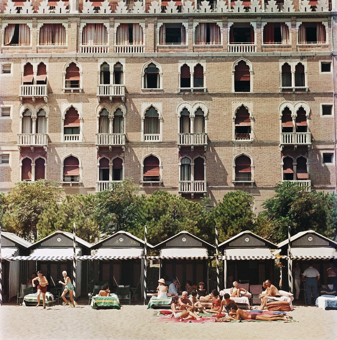 Slim Aarons Official Estate Print - Hotel Excelsior: 1957 (Printed later): Title: Slim Aarons Official Estate Print - Hotel Excelsior: 1957 (Printed later) Description: Hotel Excelsior The beach front of the luxurious Excelsior Hotel on the Venice Lido, 1957. 48x48" / 122 x