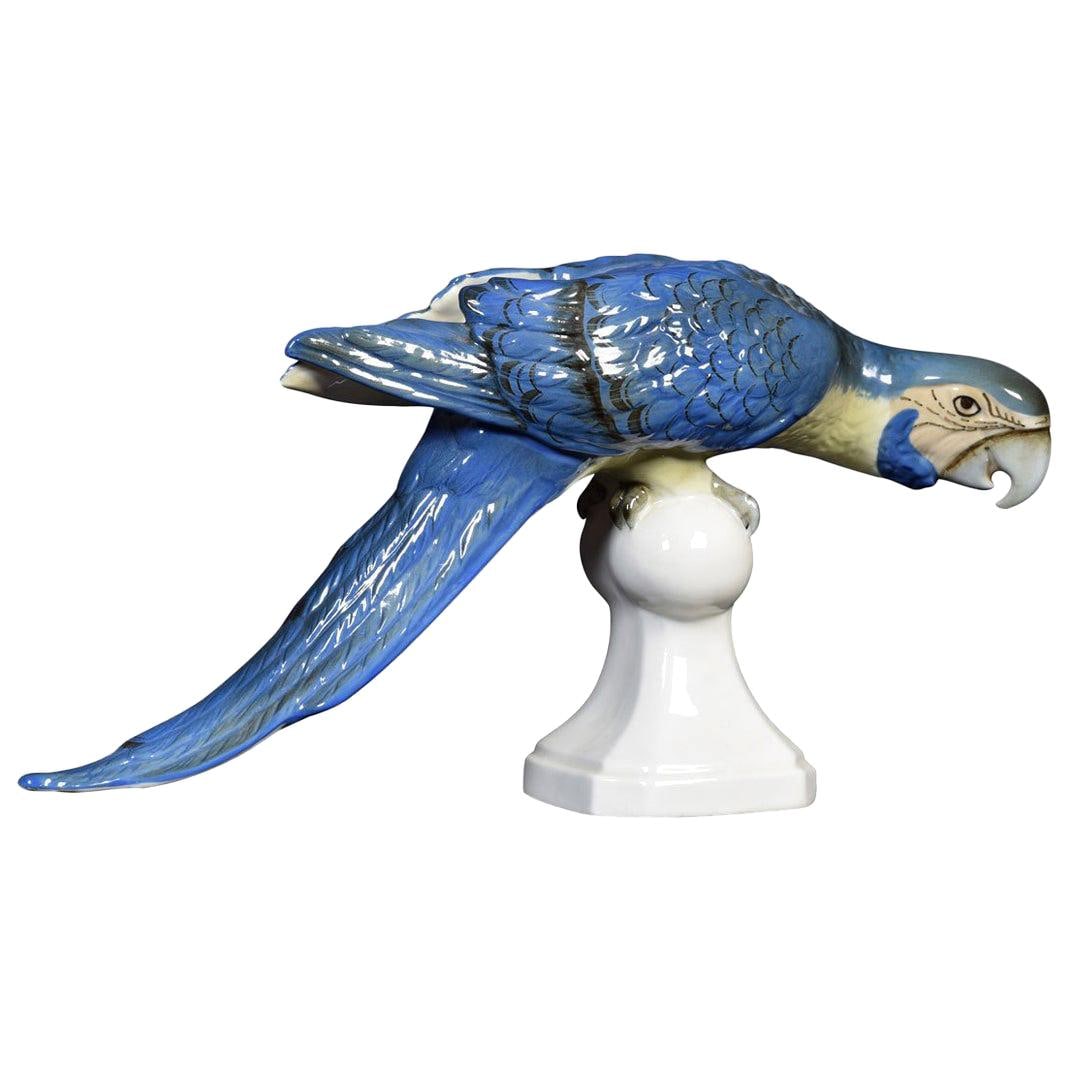 Midcentury Tropical Ceramic Blue Macaw by Royal Dux: Title: Midcentury Tropical Ceramic Blue Macaw by Royal Dux Description: Royal dux ceramic statue of a blue macaw, perched on a stand in typical inquisitive stance. Having a pink triangle to base,