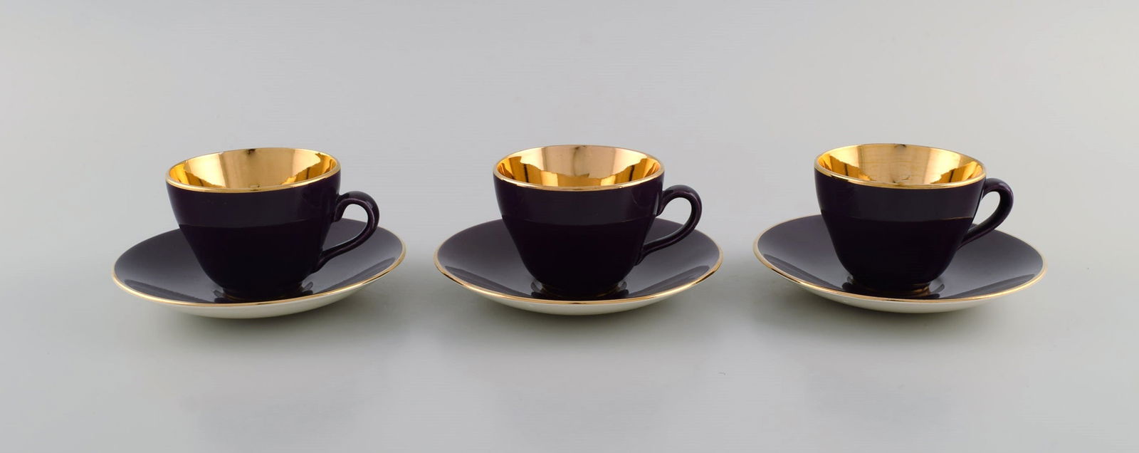 Three Royal Copenhagen / Aluminia Confetti mocha cups with saucers in purple glazed faience with: Title: Three Royal Copenhagen / Aluminia Confetti mocha cups with saucers in purple glazed faience with interior gold. Mid-20th century. Description: Three Royal Copenhagen / Aluminia Confetti mocha