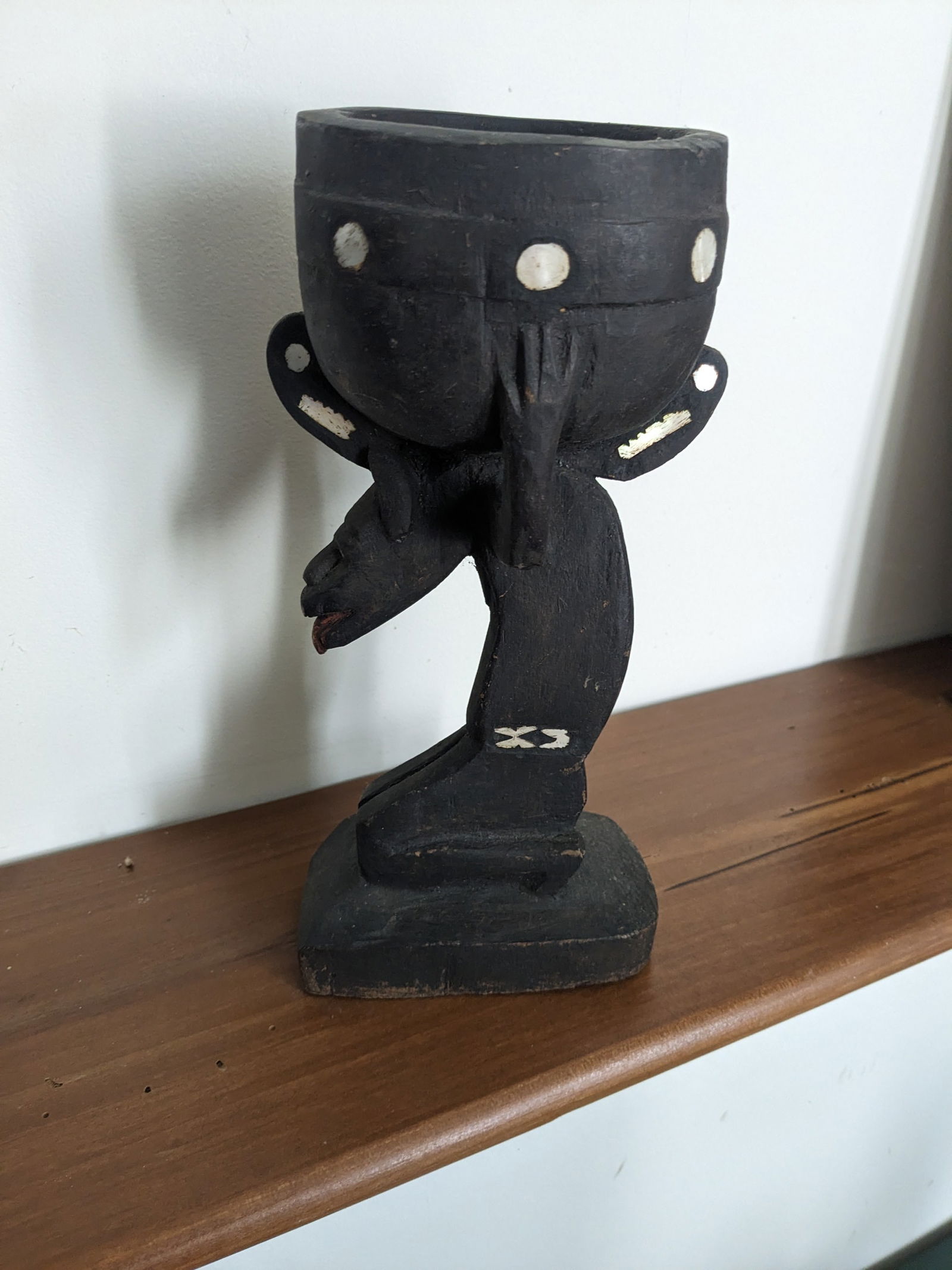 Ceremonial Cup: Title: Ceremonial CupDescription:Carved wooden cup held by a figure on knees, with inlayed shell. Date/Period: Mid 20th centuryMaterials:woodDimension:10" x 4" x 5" Reserve: $80.00 