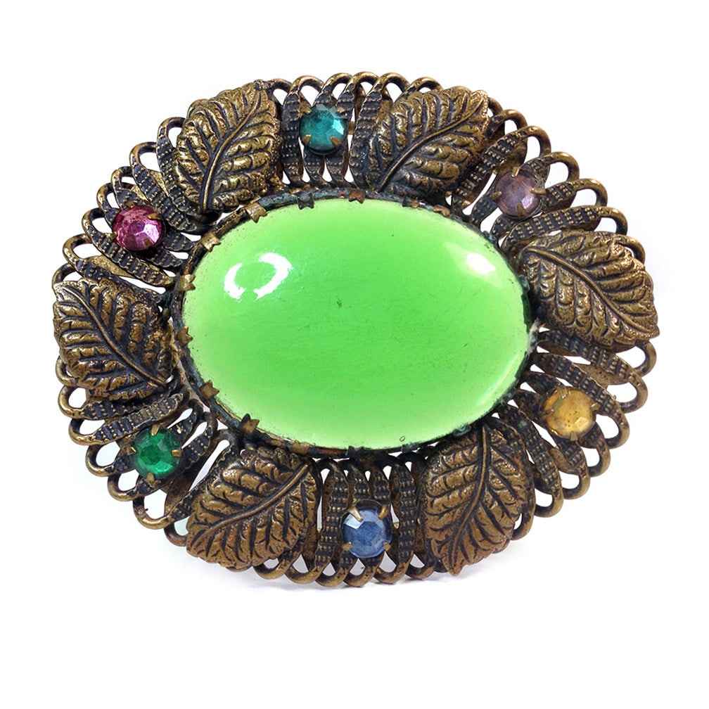 Czecho-Slovakia Green Dress Clip: This is a Czecho-Slovakia (1918-1938 ) dress clip with a large Kelly green poured glass stone in a leafy brass frame set with prong-set multicolored rhinestones. Signed in the back. Can also be worn