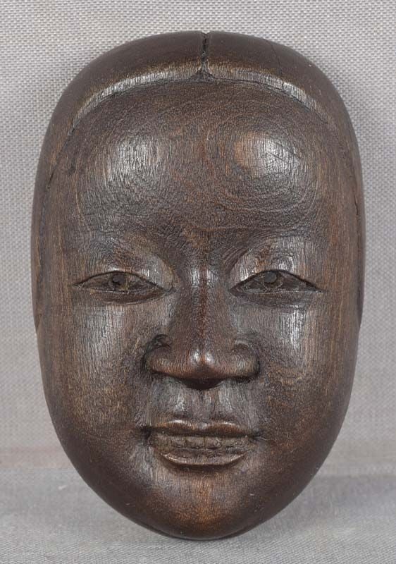 19c netsuke mask of KO-OMOTE: Late 19th century wooden netsuke representing a theatrical mask of Ko-Omote - for information on this character representing young women see NETSUKE MASKS by Bushell, p. 103. Excellent crisp detailing