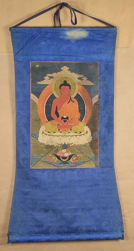 Early 19c Tibetan thangka BUDDHA AMITABHA: Early 19th century Tibetan thangka in original mounts depicting Buddha Amitabha seated on a lotus throne holding an alms bowl in his hands, sun and moon among clouds behind him and a pile of offerings