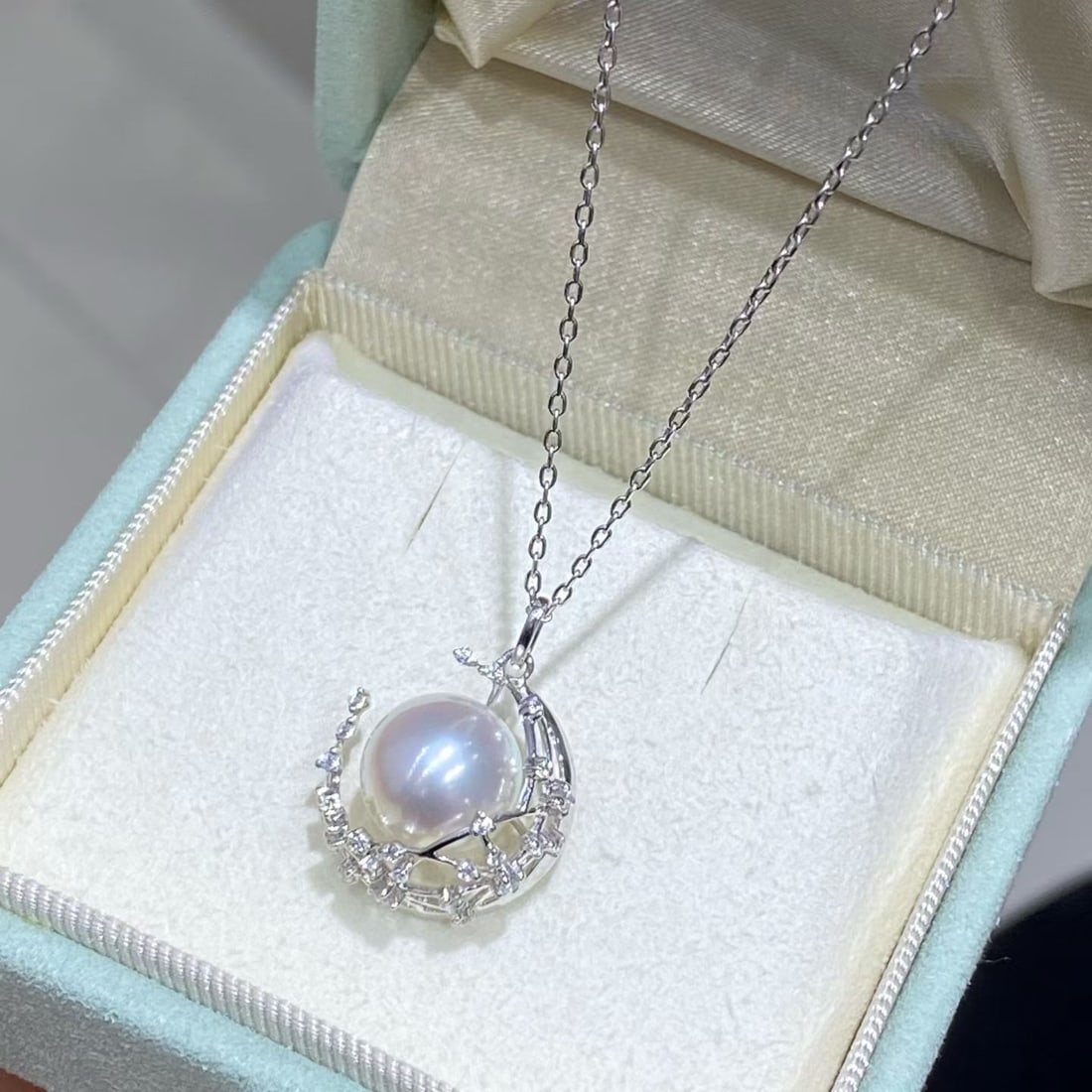 18K Gold Natural Pearl Crescent Moon Pendant: Title: 18K Gold Natural Pearl Crescent Moon Pendant Description: This pendant showcases a 10-11mm natural saltwater pearl, renowned for its perfect round shape and intense luster. The unique crescent